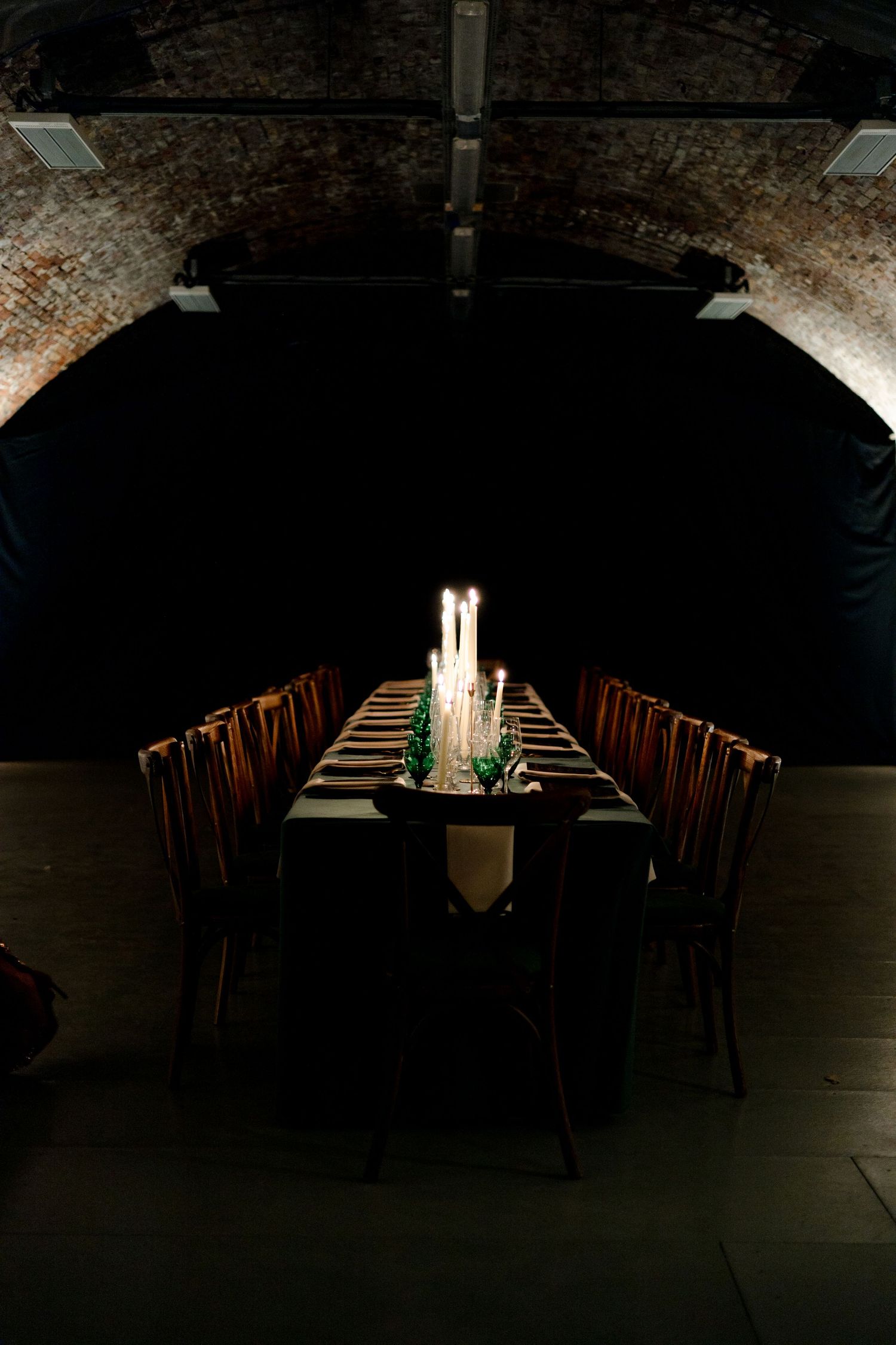 Dark atmospheric dining room setup with long tables and moody lighting.