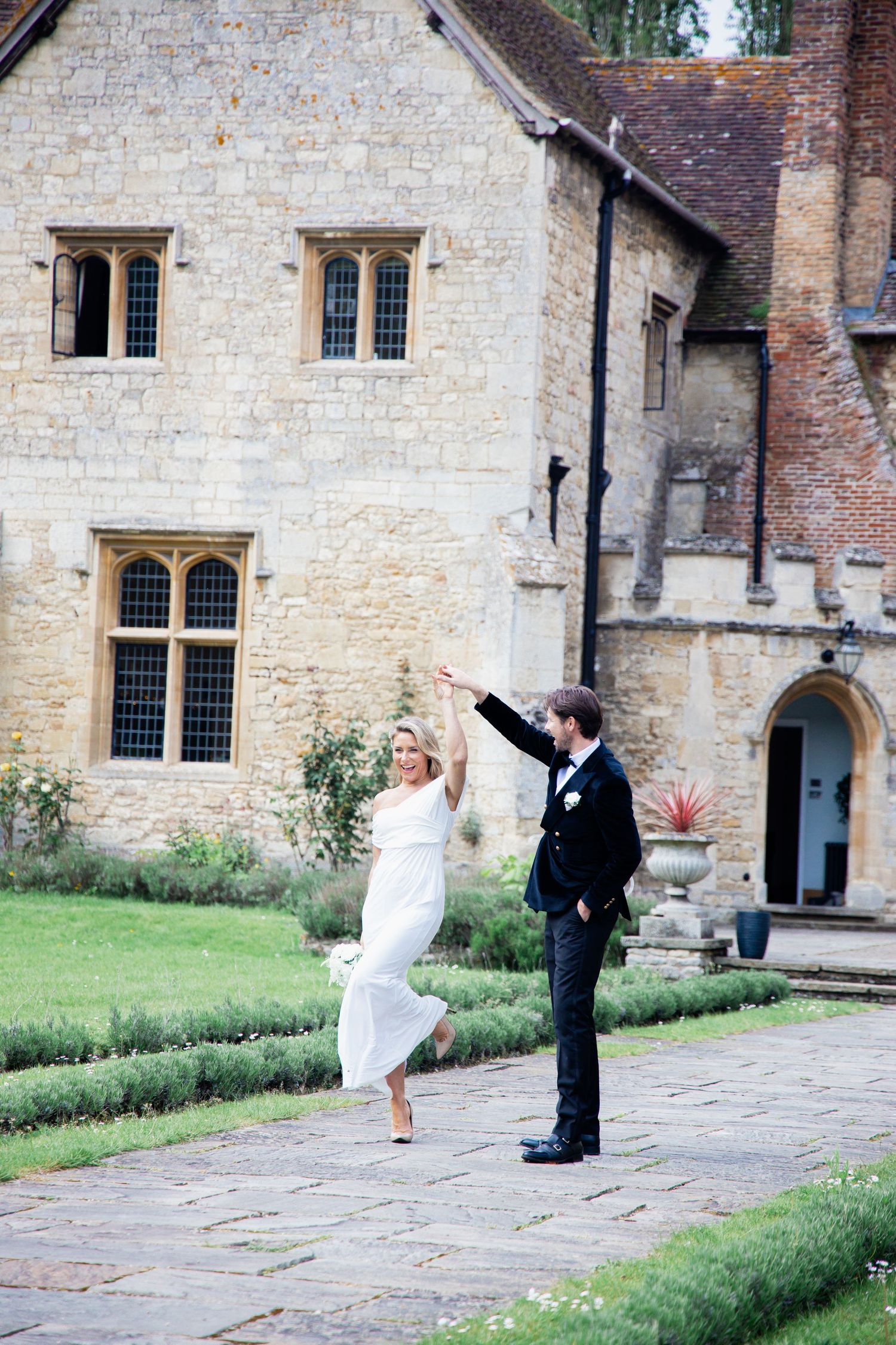 A joyful wedding dance captured outside a historic stone building.