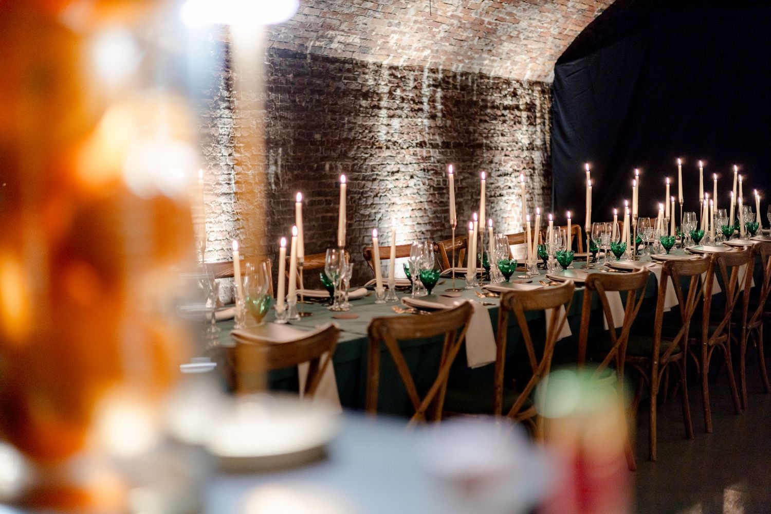 Rustic brick wall venue with long dining tables set for an elegant event.