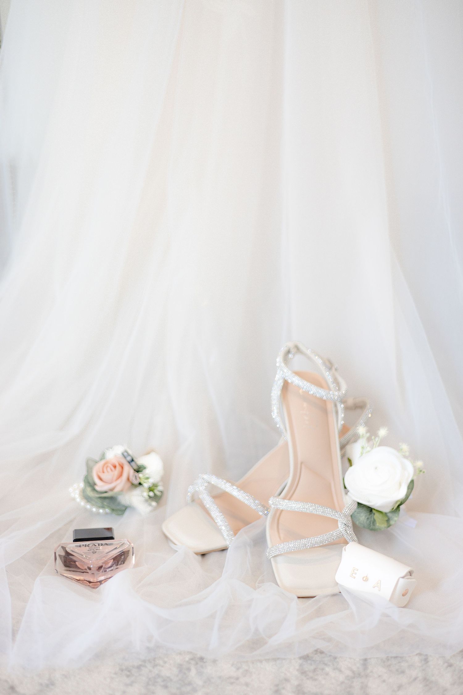 Delicate bridal shoes and floral accessories arranged against a soft white backdrop.
