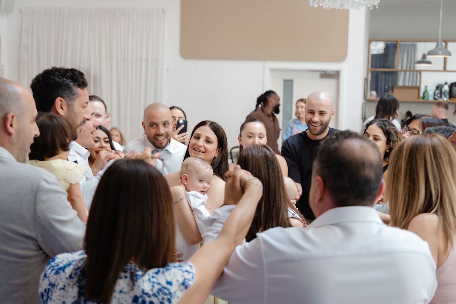 Party guests enjoying themselves on a dance floor under a crystal chandelier.