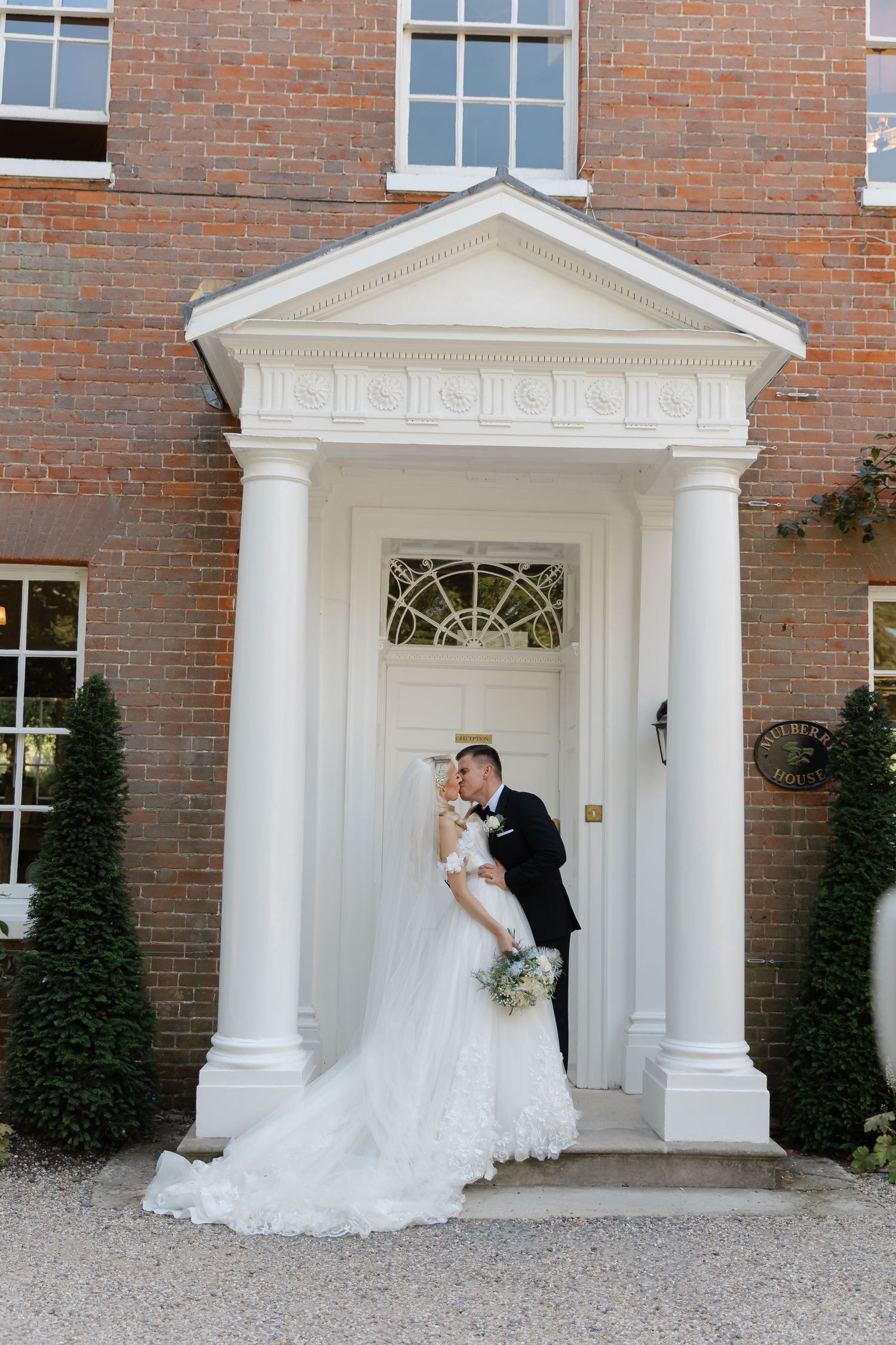 Romantic wedding portrait in front of elegant Georgian doorway with white columns.