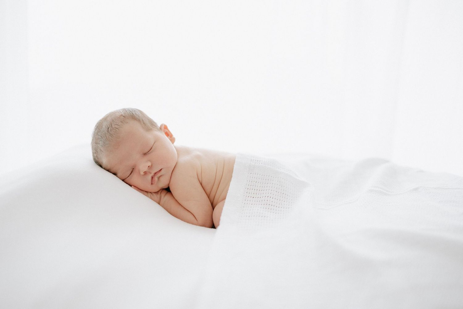 Simple white newborn portraits capturing peaceful sleeping moments.