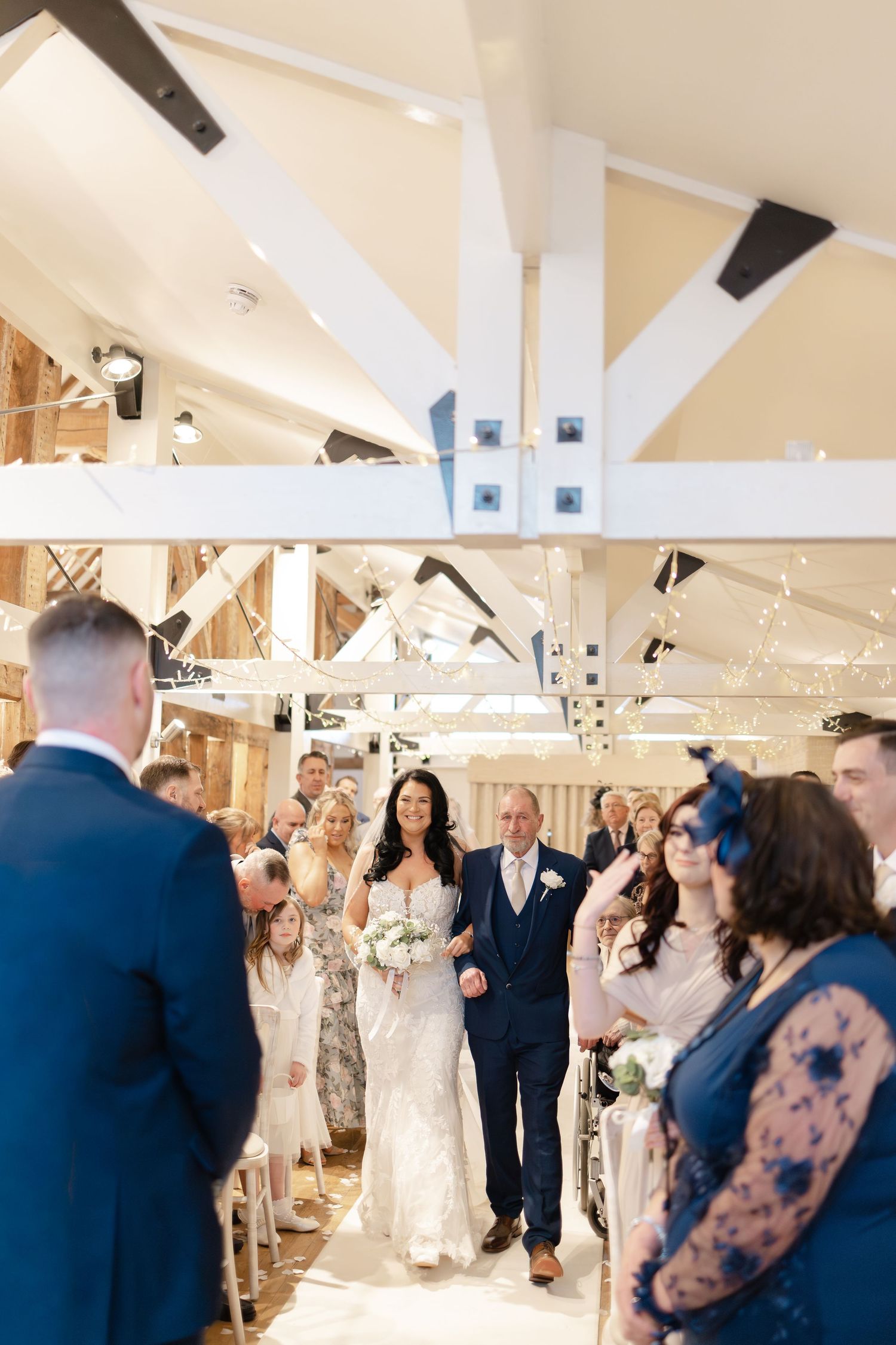 Wedding celebration in modern venue with high ceilings and string lights.