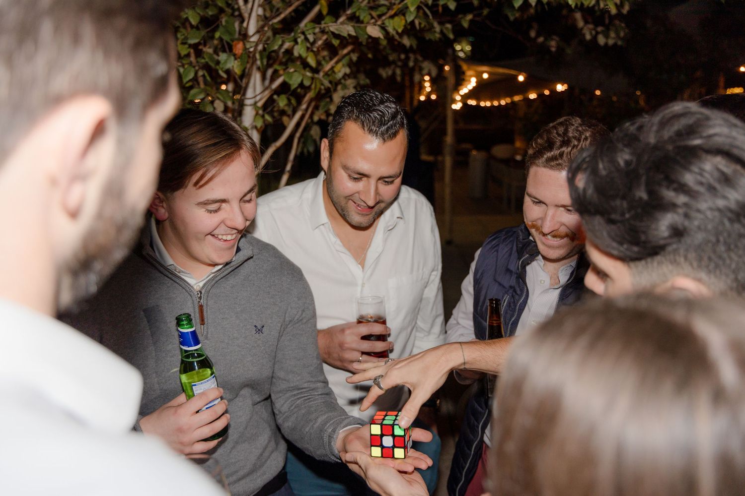 People laughing and socializing at an indoor evening party with ambient lighting.