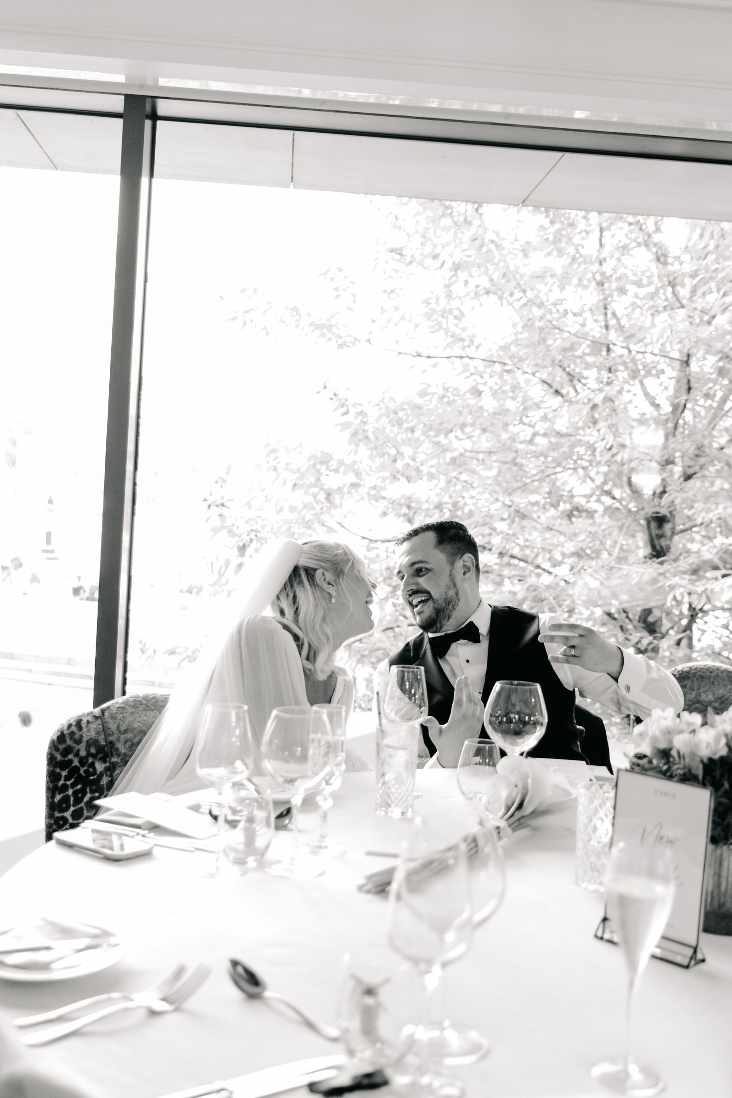 Wedding guests enjoying a celebratory meal at an elegant reception with bright natural lighting.