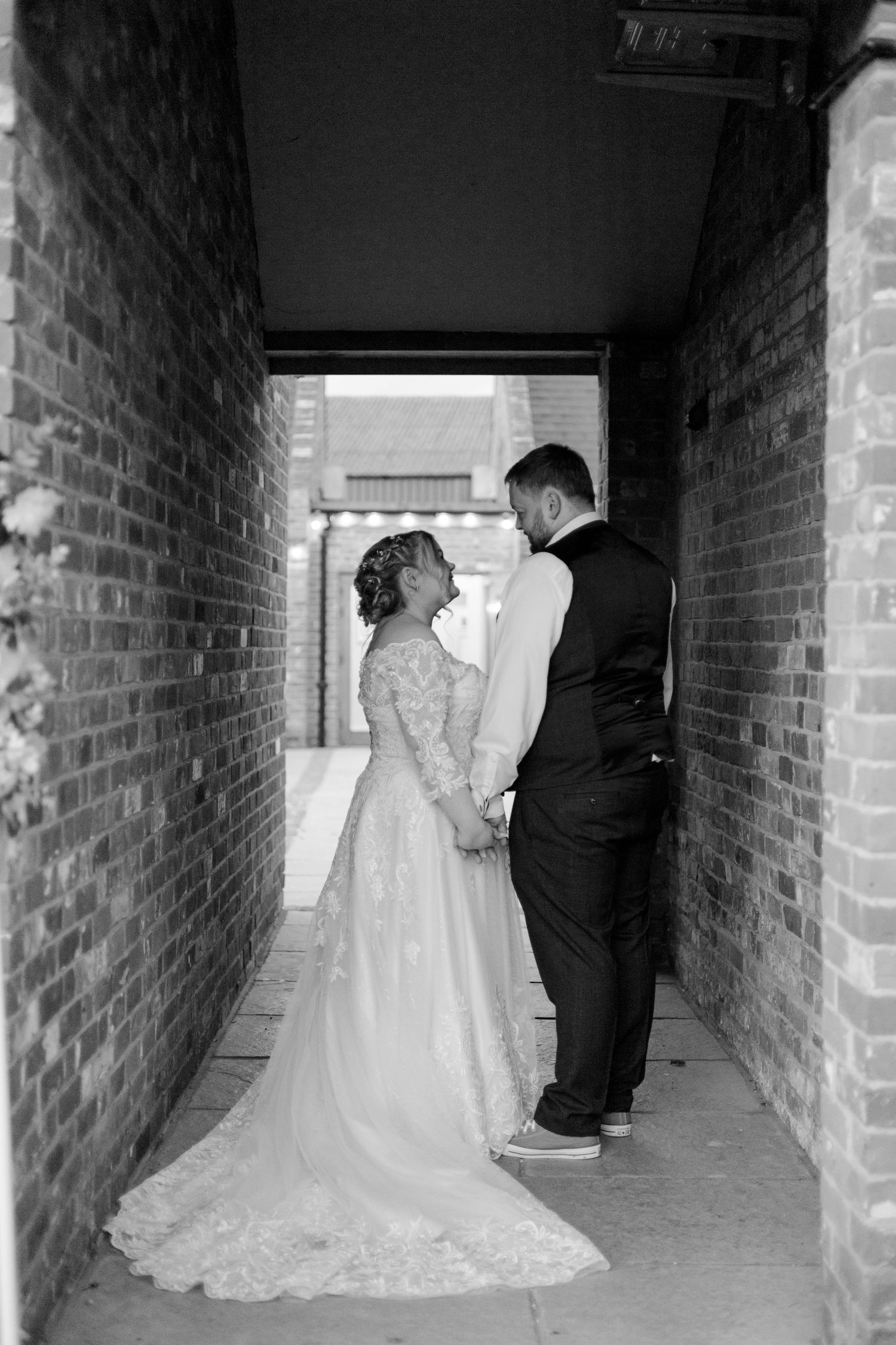 A bride and groom holding hands in a brick passageway during their wedding.