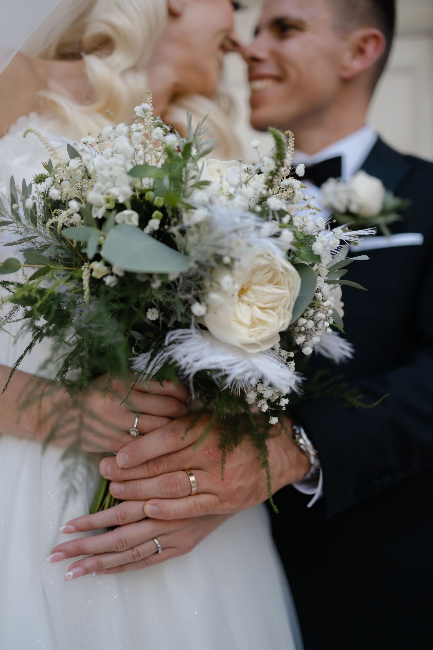 Elegant white and green wedding bouquet held between bride and groom.