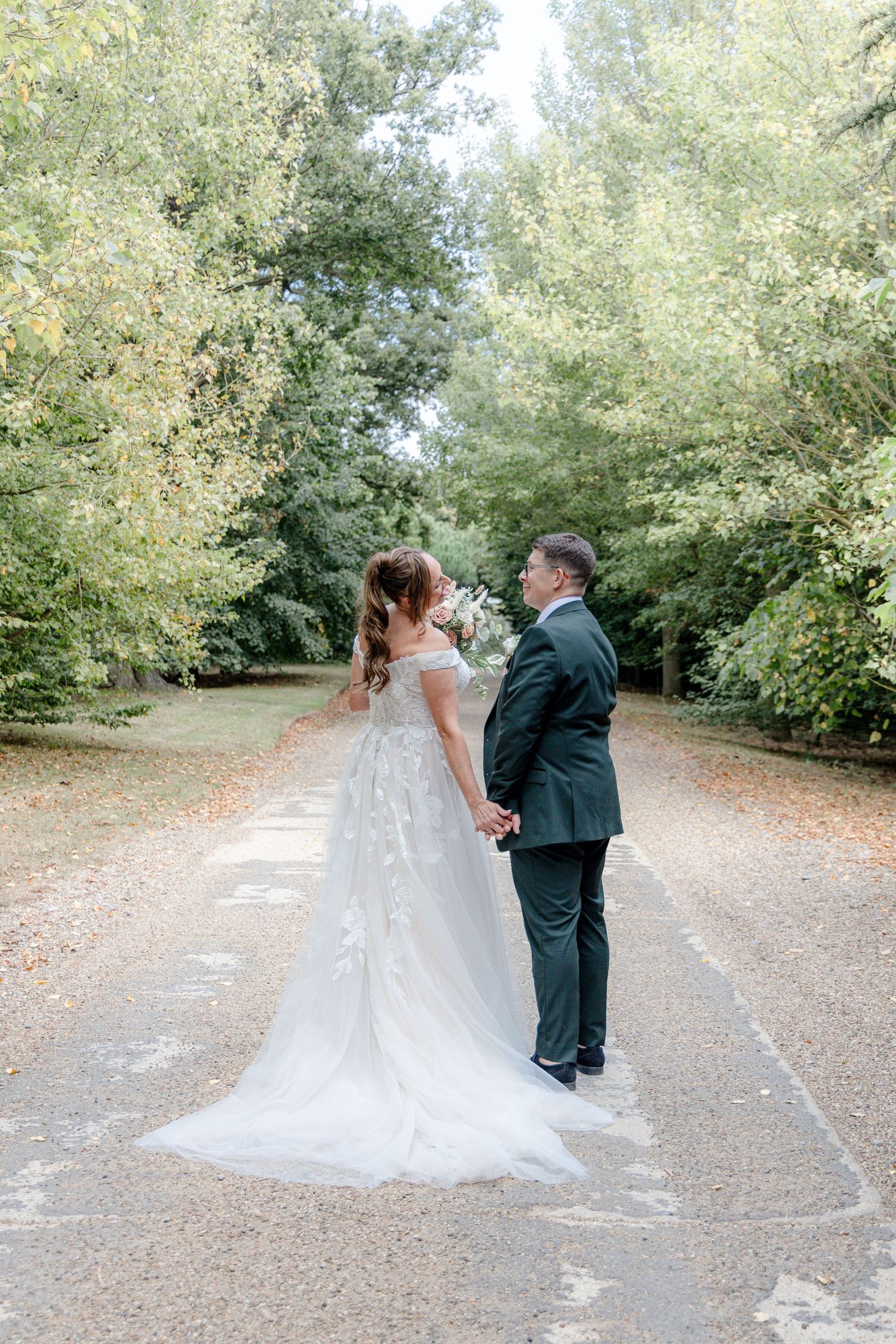 Wedding couple photographed on a tree-lined path in romantic poses.