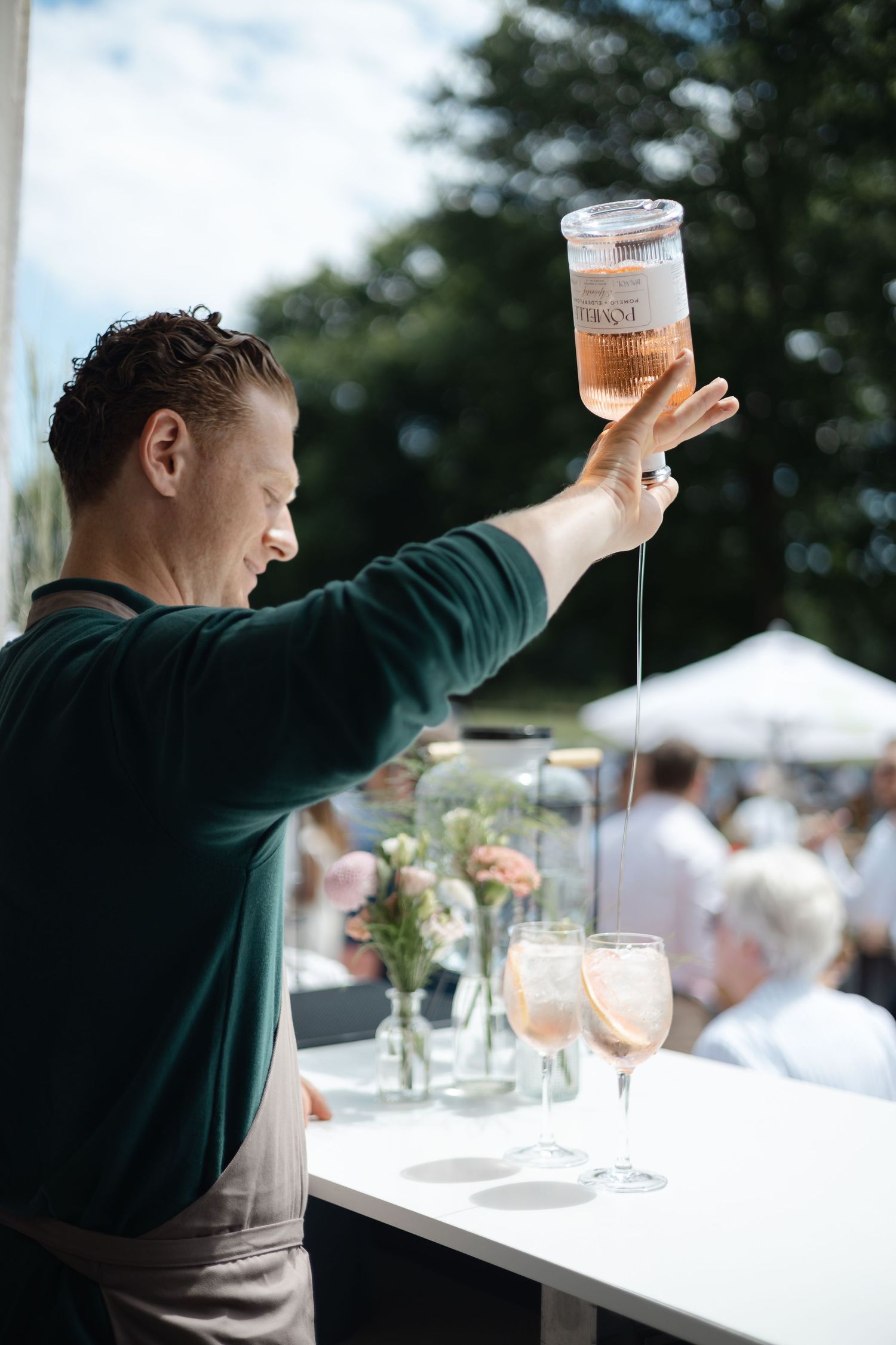 Person pouring and serving drinks at an outdoor event.