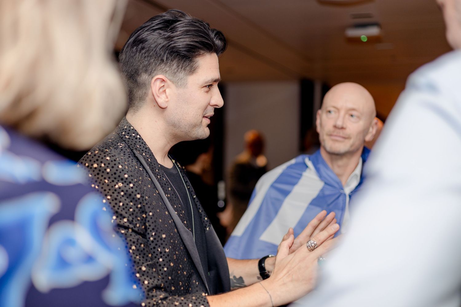 People mingling and conversing at an indoor social function.