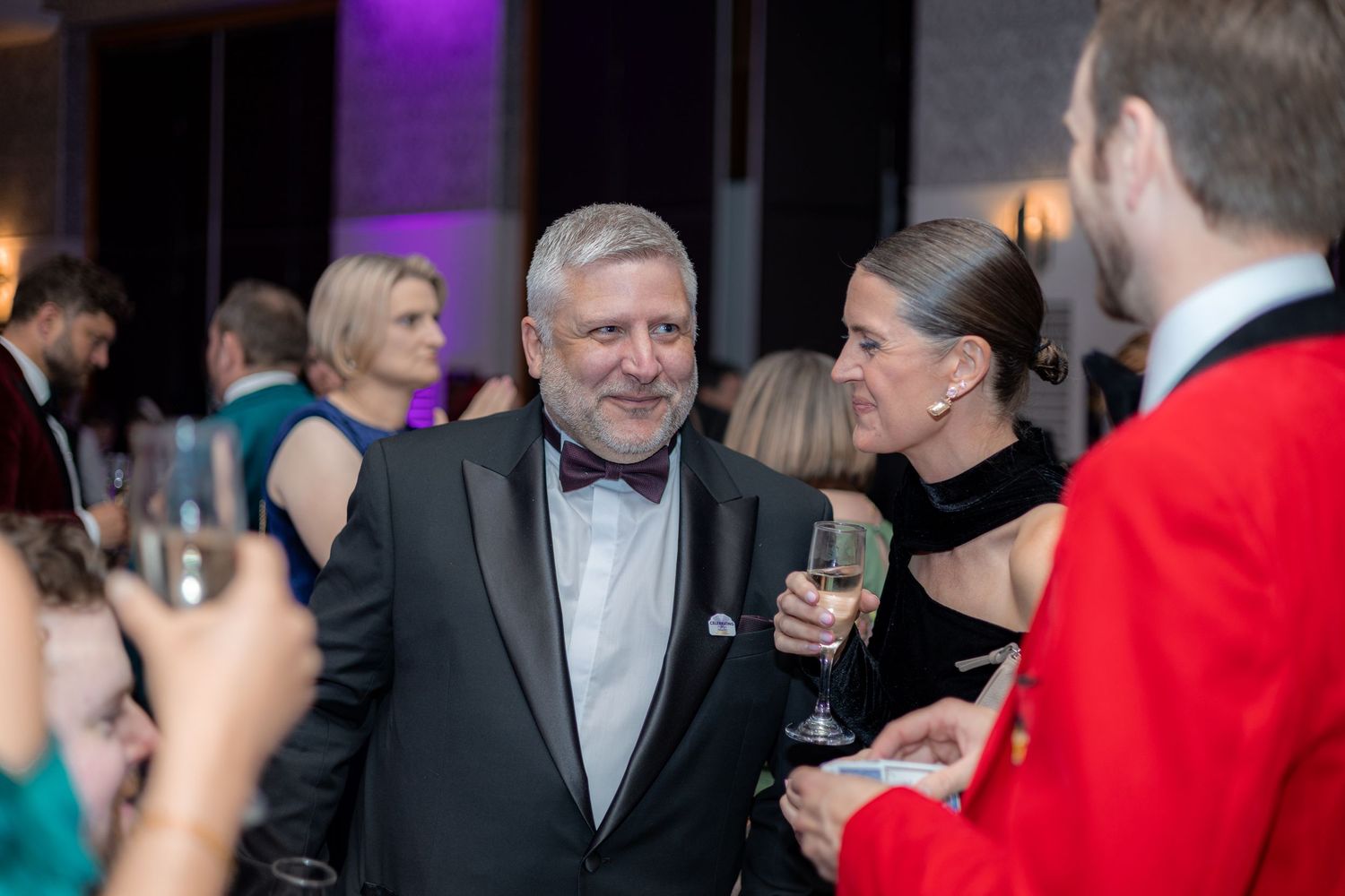 Guests engaged in conversation at an elegant evening reception with mood lighting.