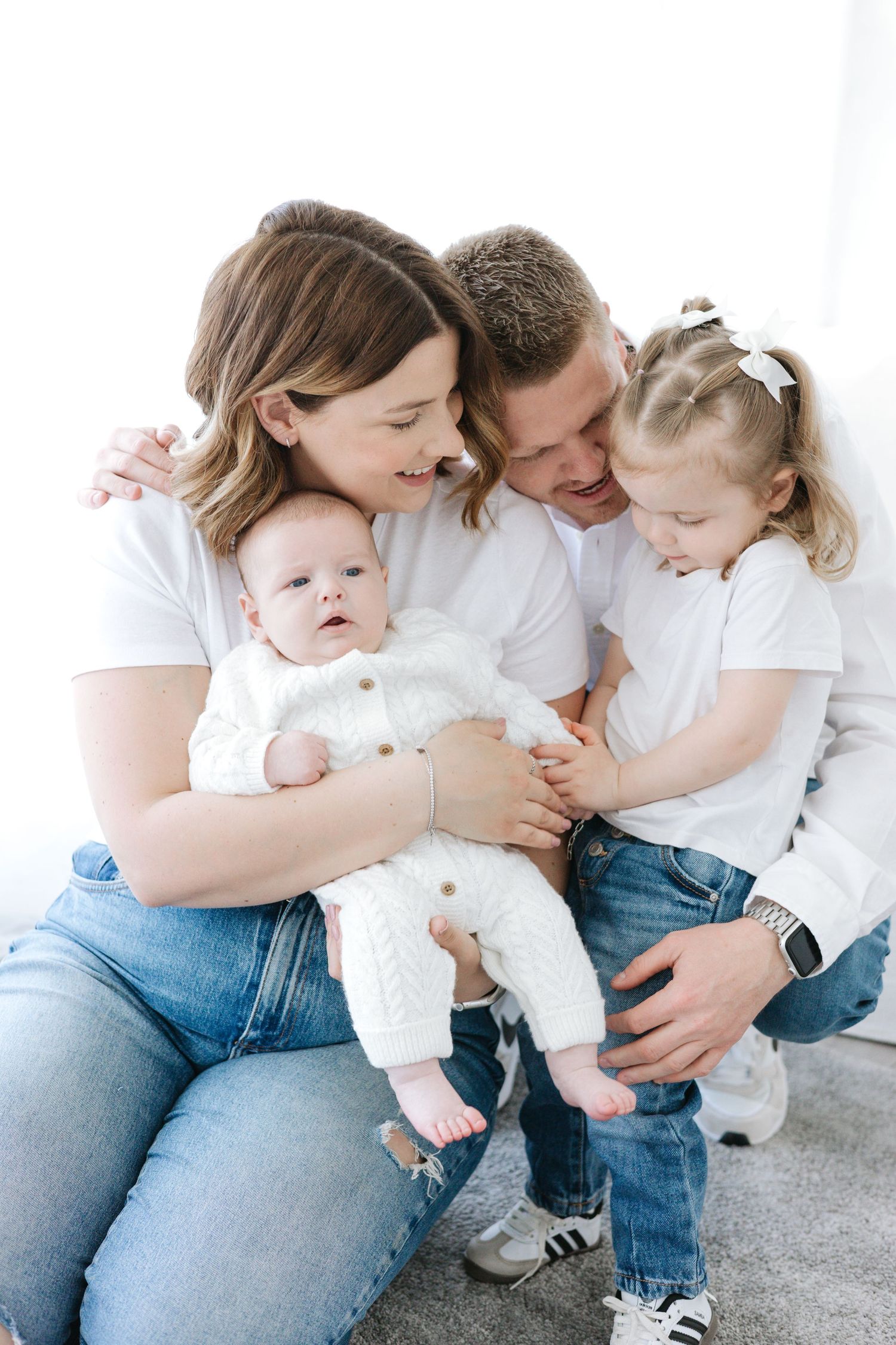 Family cuddles together in a series of intimate black and white photos wearing casual white tops and jeans.