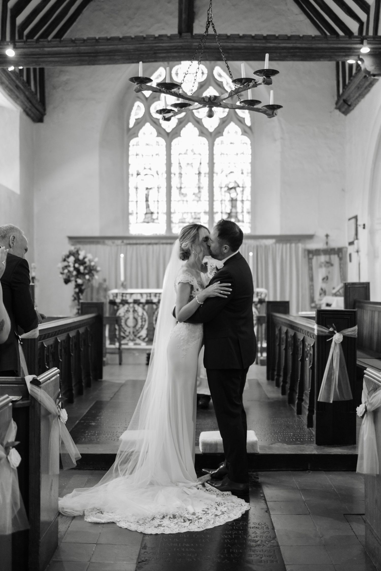 Black and white photo of wedding ceremony inside historic church with wooden beams.