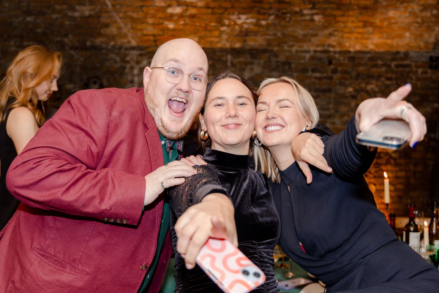 Party guests enjoying drinks and laughter at an elegant brick-walled venue.