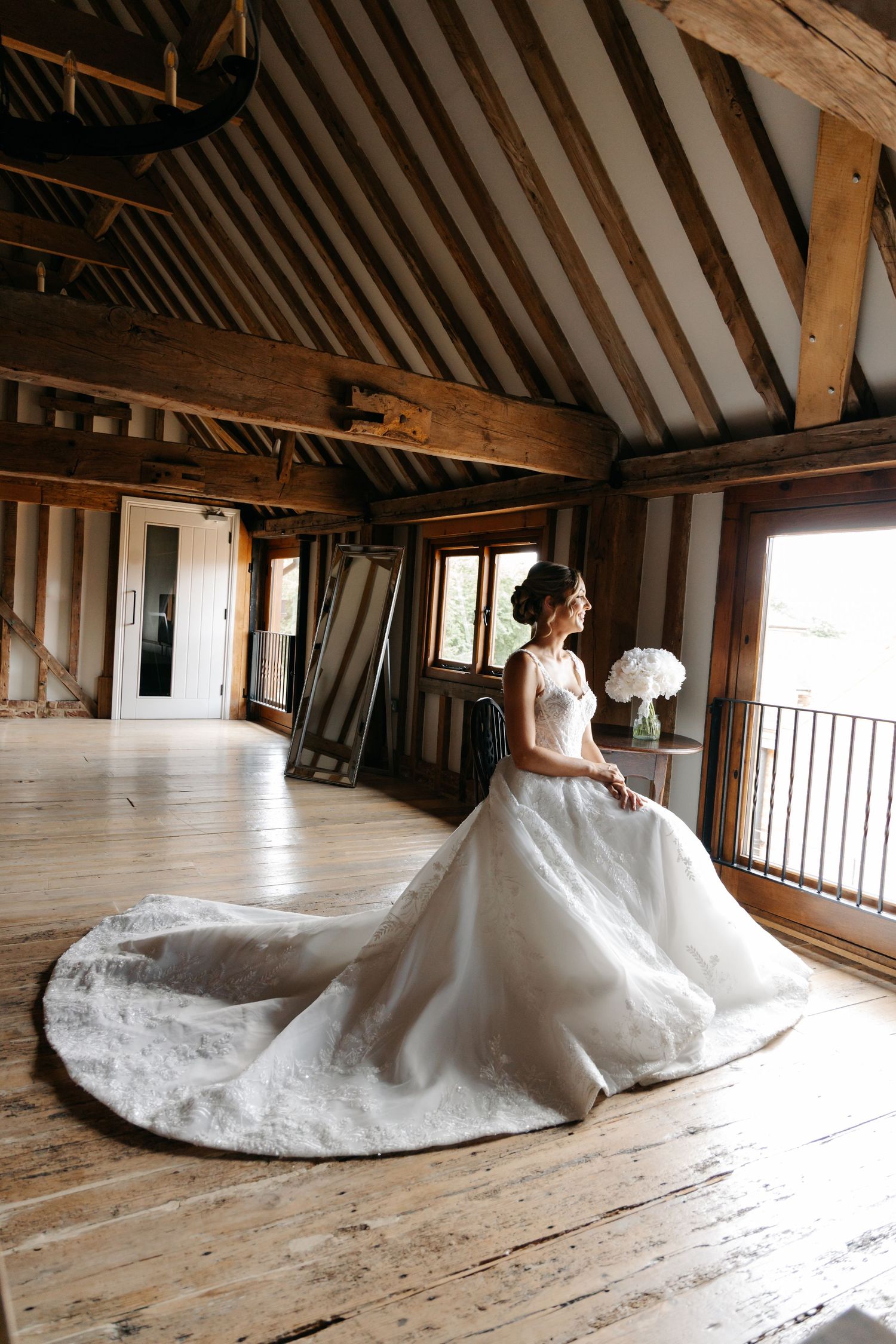 Dramatic bridal portraits showing full wedding gown train in rustic wooden loft setting.
