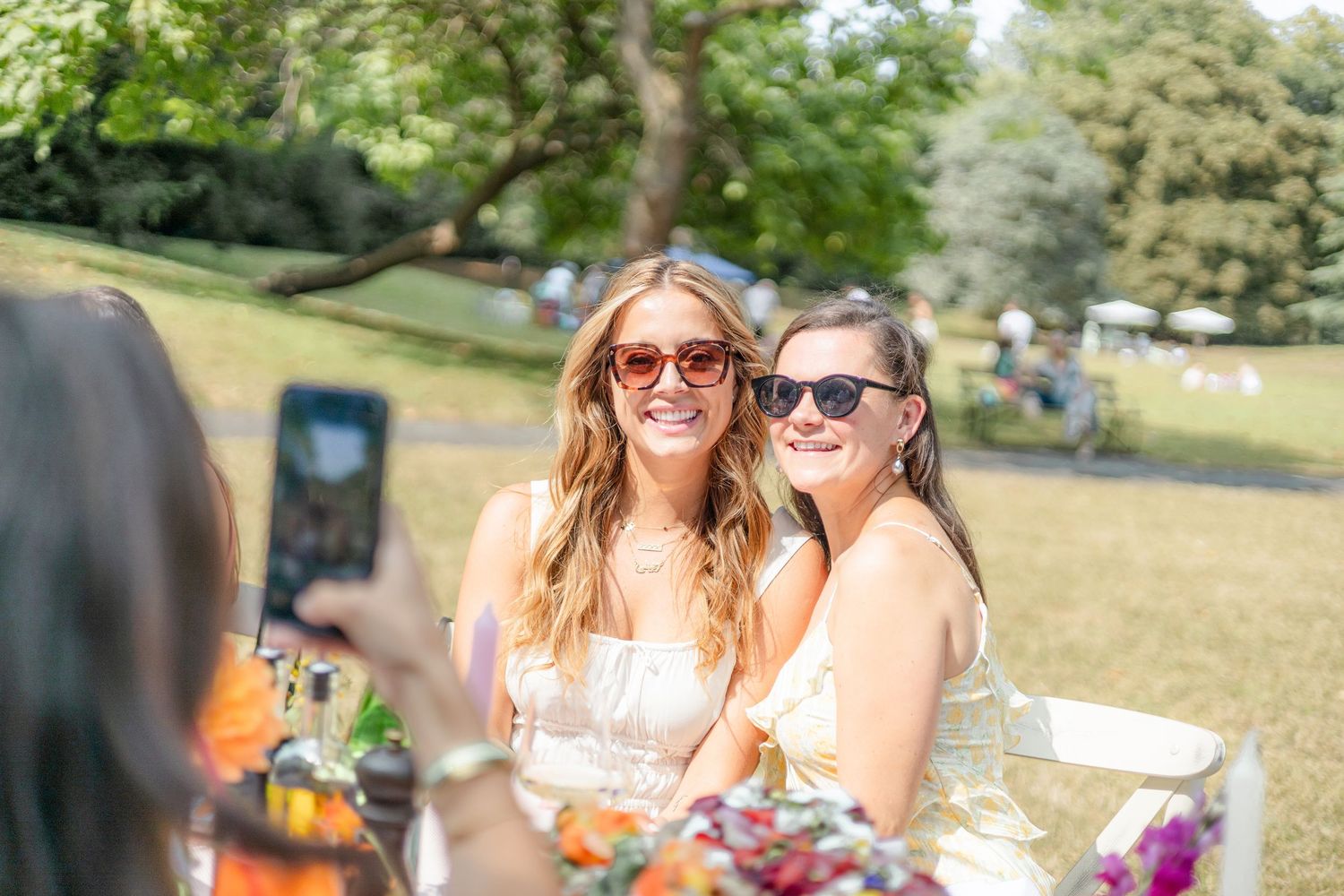 Sunny outdoor celebration with decorated tables and party guests enjoying themselves.