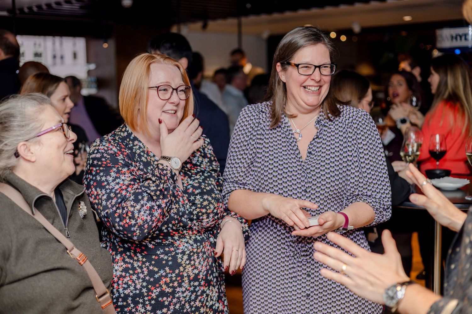 Group of friends laughing and enjoying themselves at a social gathering in a casual indoor setting.