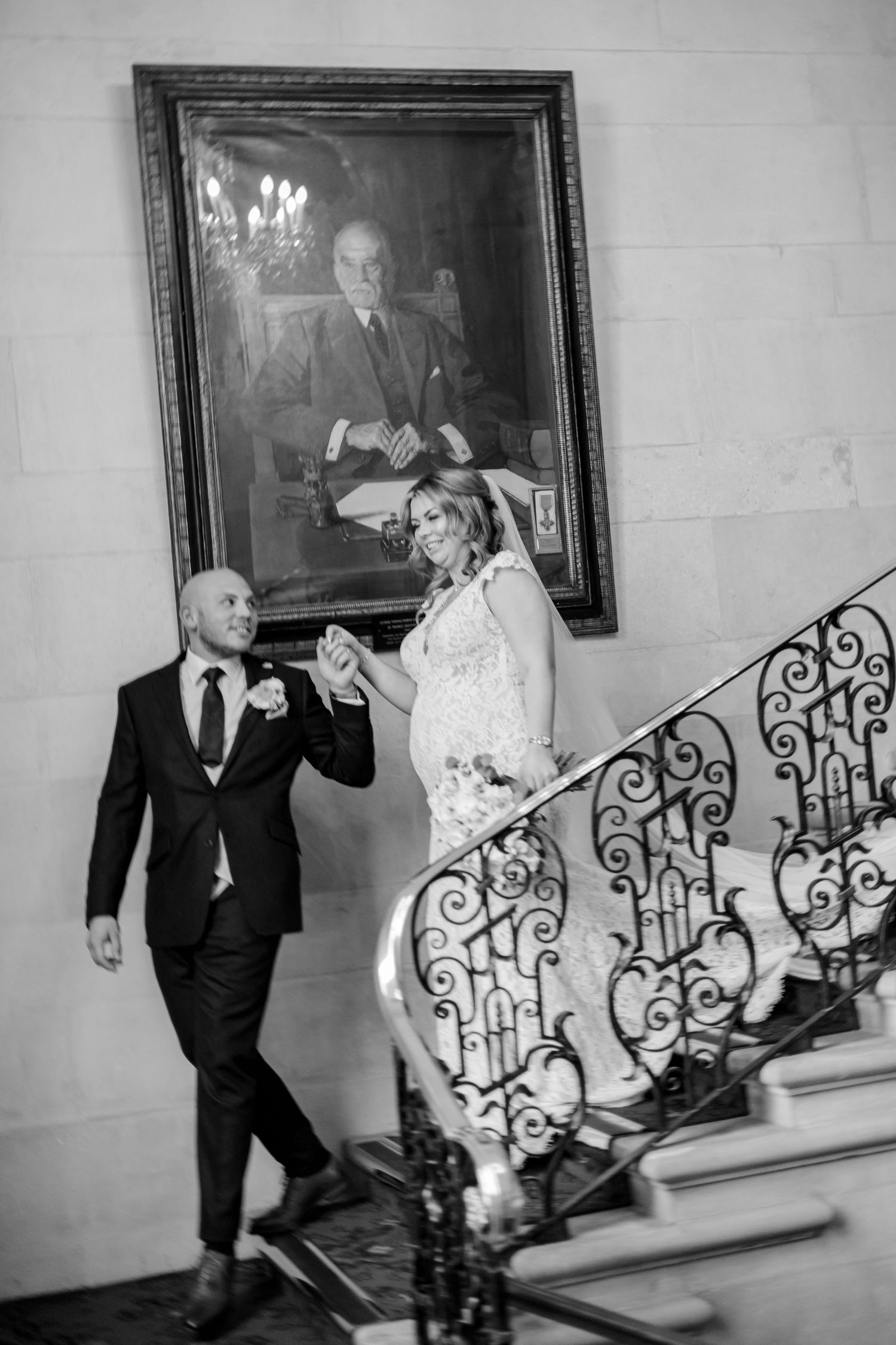 Black and white photo of playful moments on a grand staircase with ornate railings.