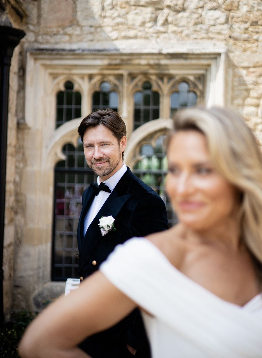 Elegant wedding portraits captured against a historic stone building with arched windows.