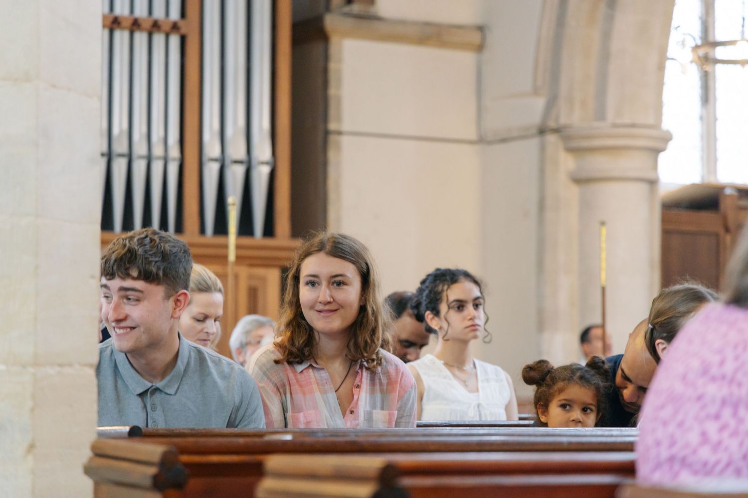 Guests seated in white church interior with stone columns and wooden pews.
