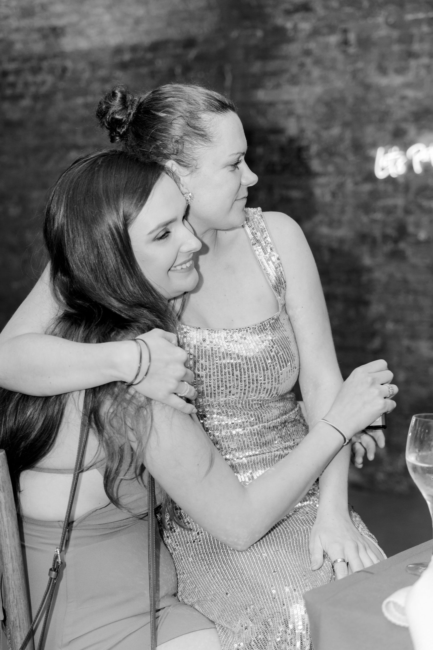 Black and white candid photo of guests embracing at formal celebration.