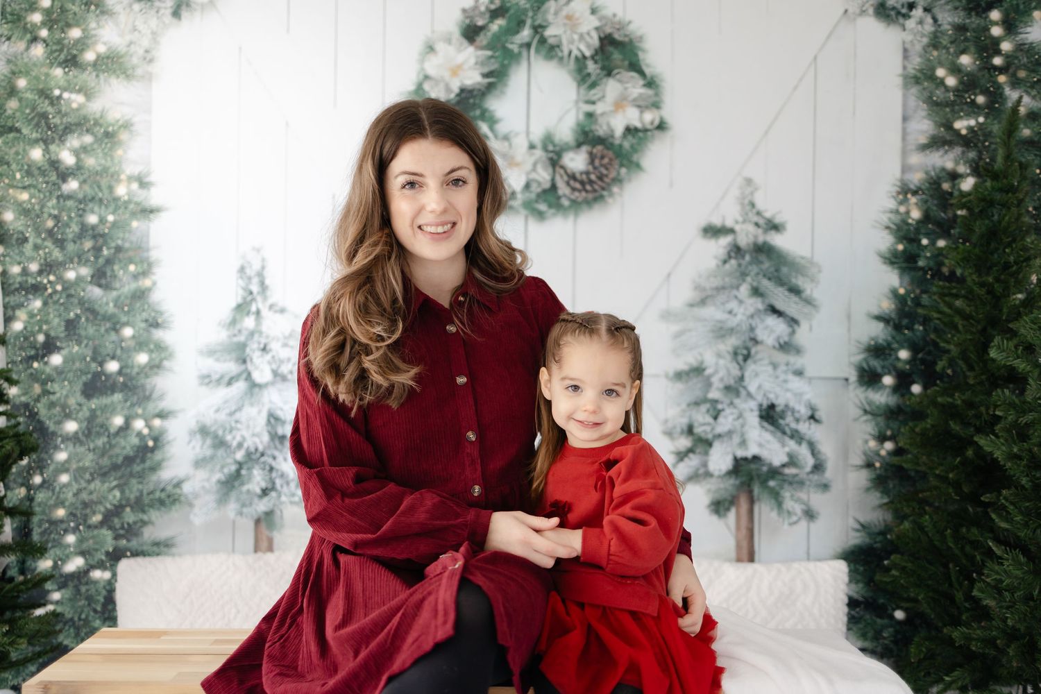 A festive holiday portrait with winter decorations and Christmas trees in the background.