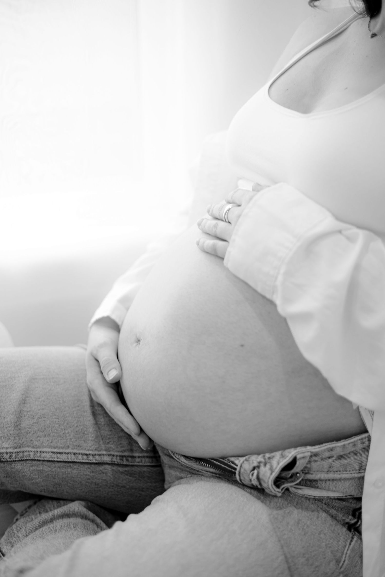 Black and white maternity photo showing pregnant belly in casual denim.