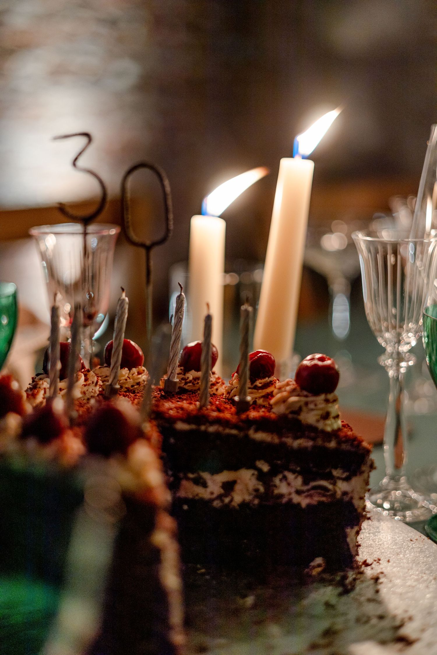 Close-up of a chocolate birthday cake with lit candles and the number 30.