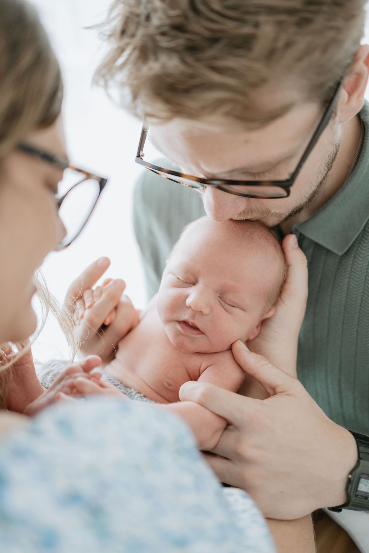 Tender moment between parent and newborn captured in soft natural light.