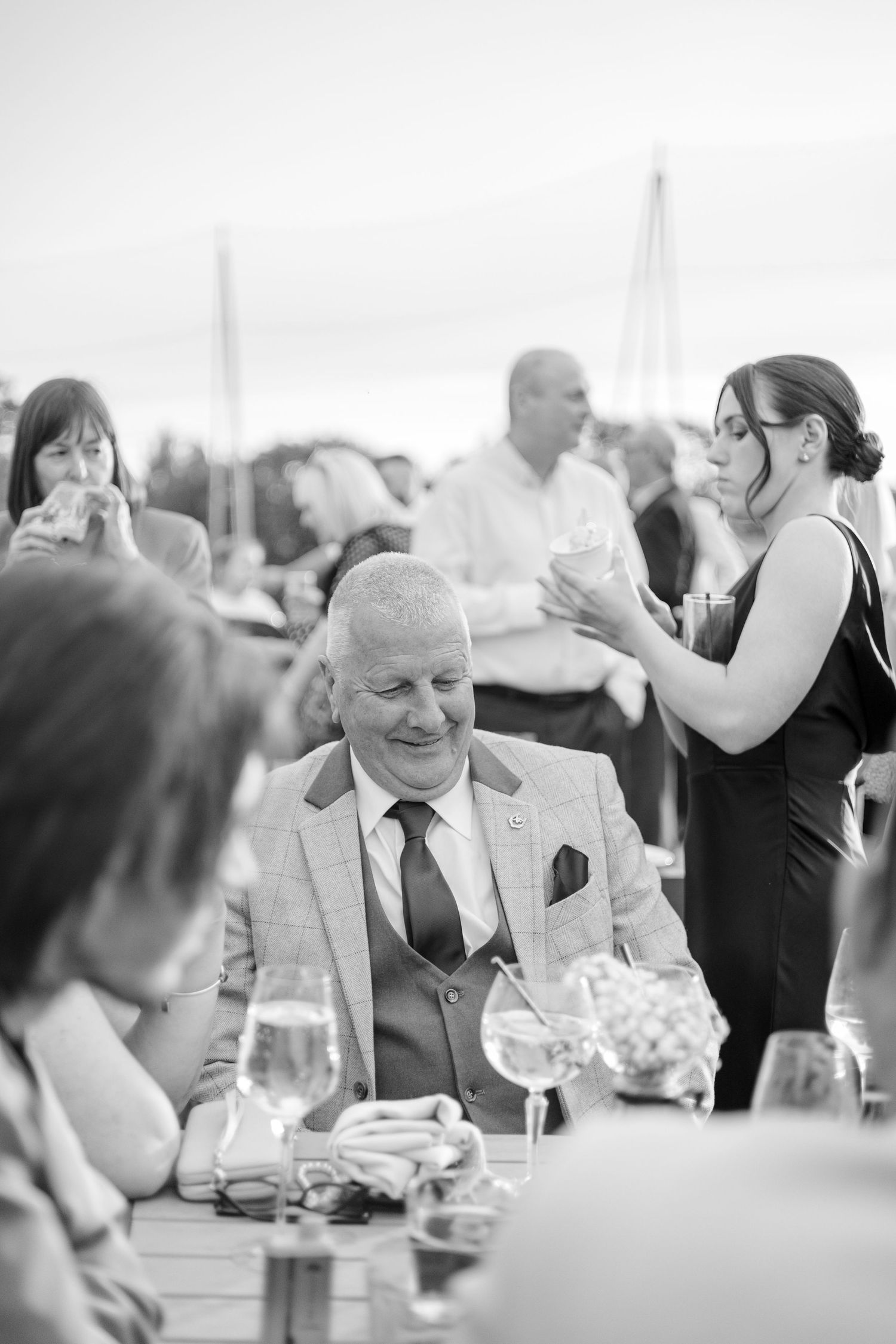 Guests enjoying conversation and drinks at an elegant formal event with table settings and glassware.