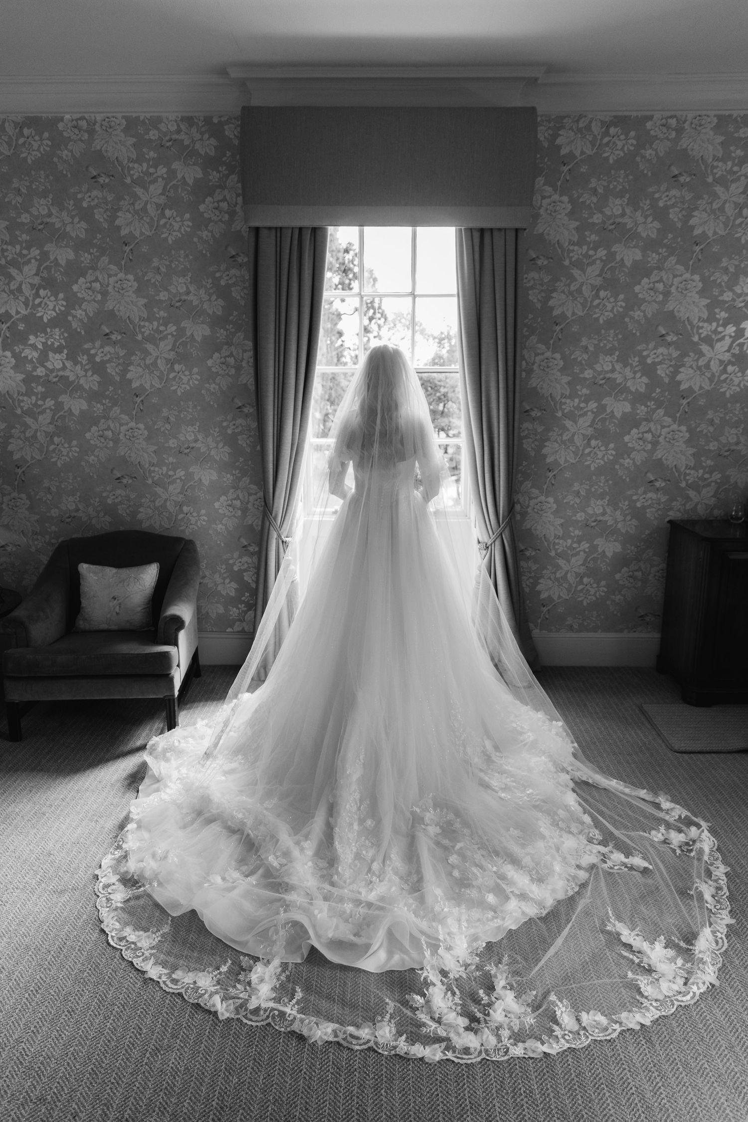 Black and white photo of wedding dress train with intricate lace details.