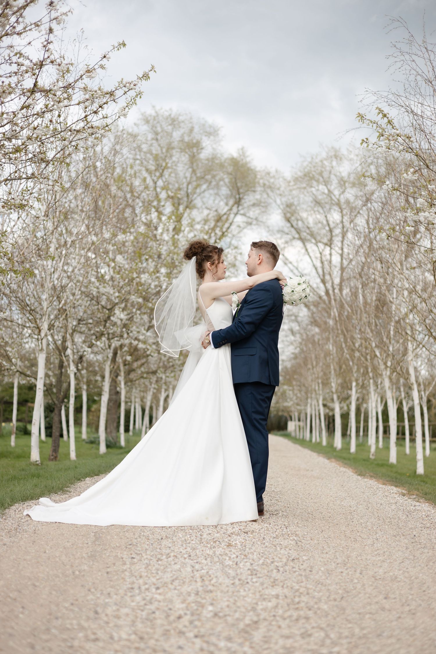 Romantic wedding portraits on a gravel path lined with white birch trees.