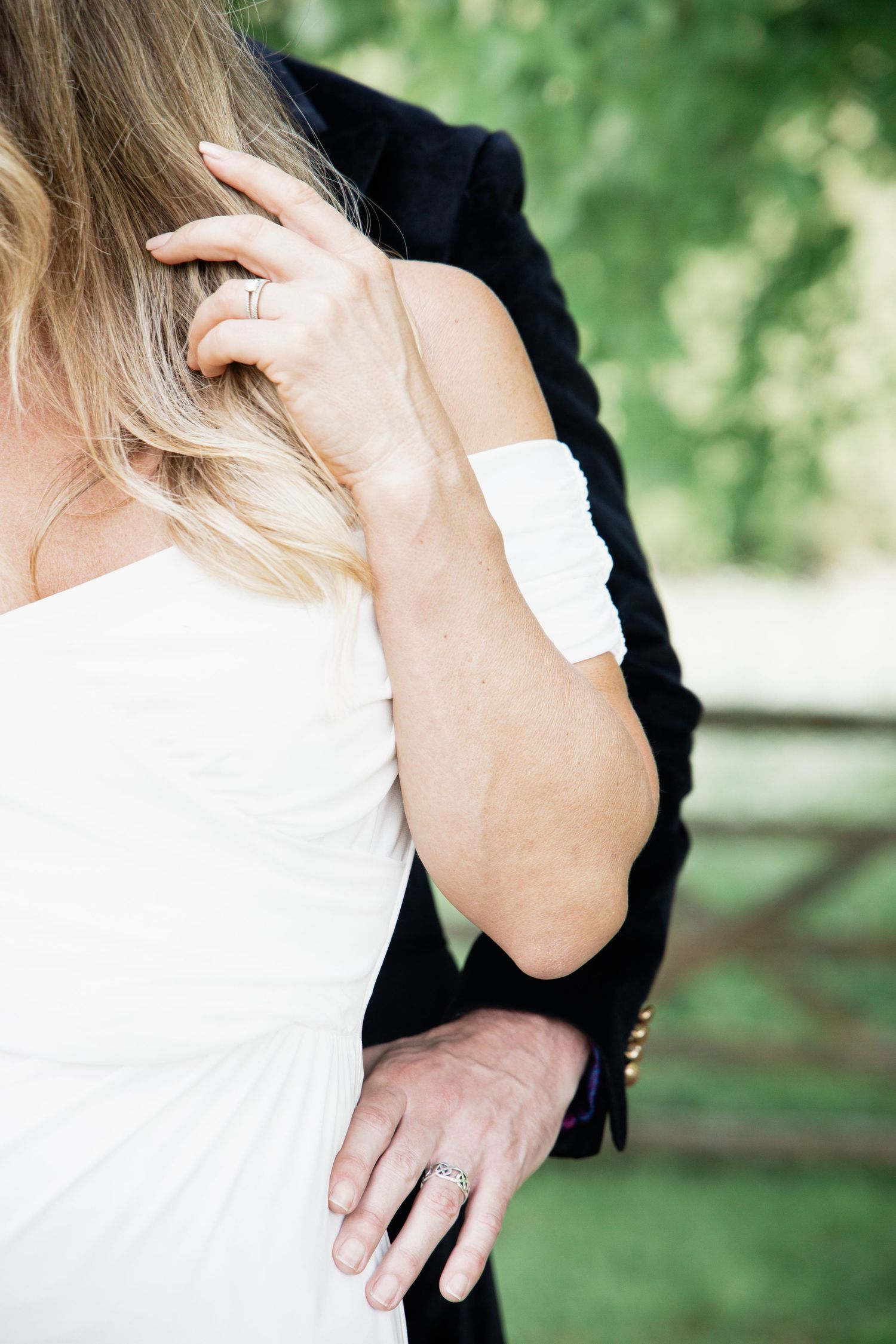 Intimate close-up of a couple embracing outdoors in wedding attire.
