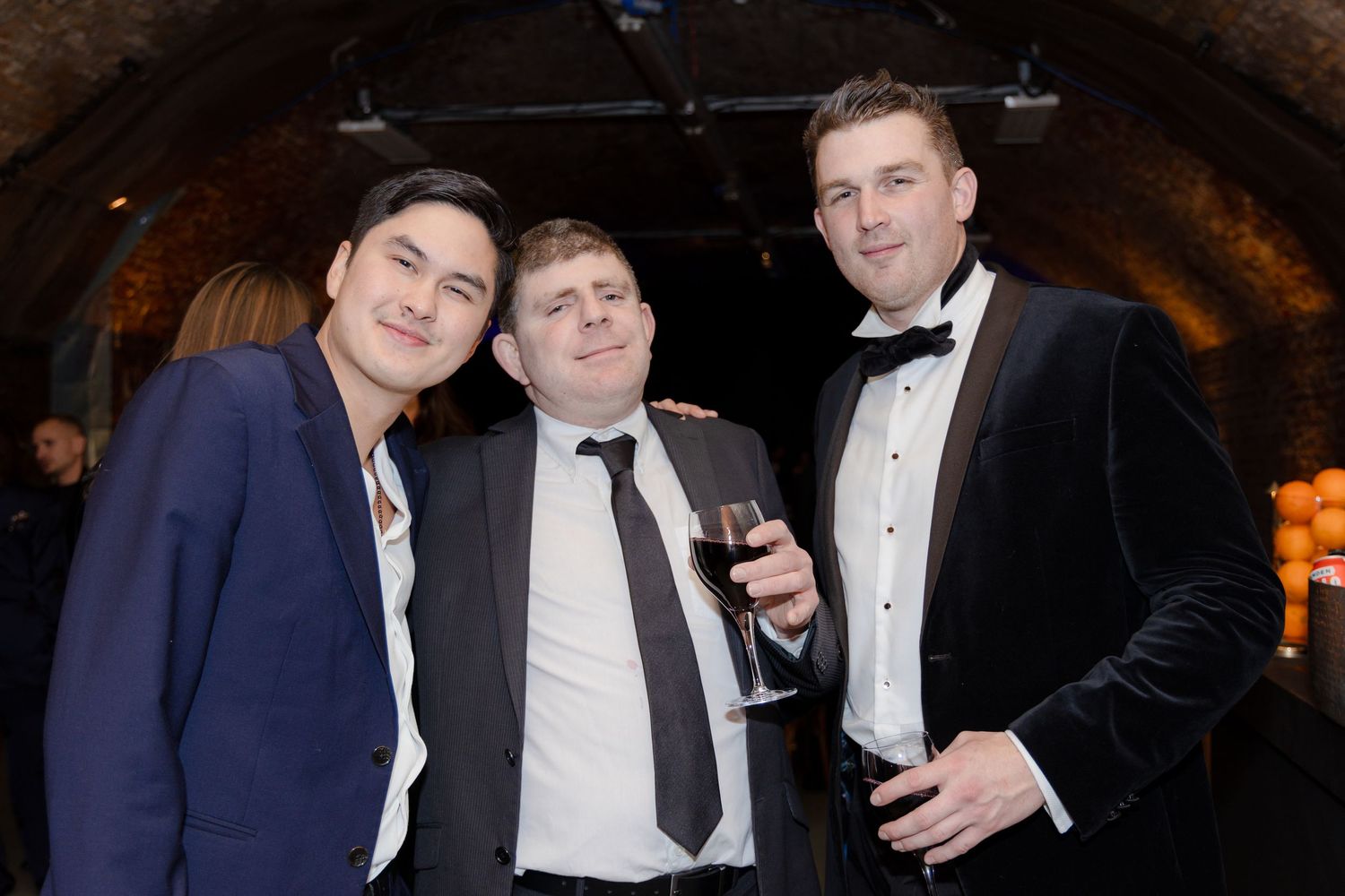 Guests in formal attire mingling and taking photos at an evening celebration.