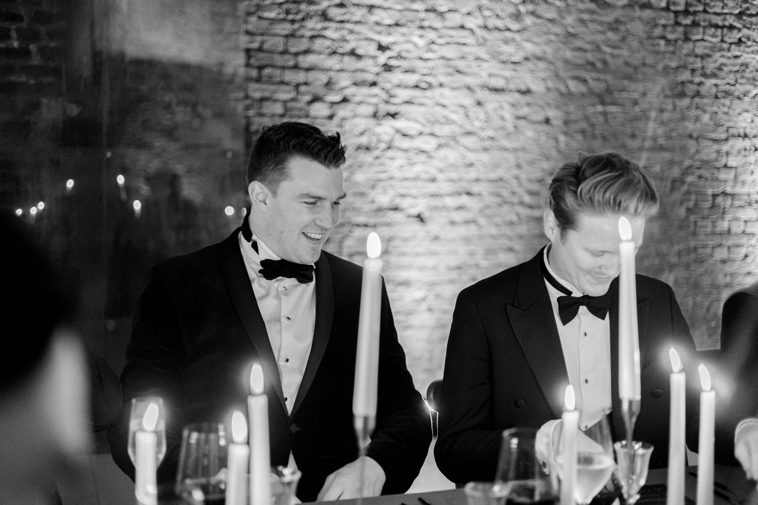 Candlelit dinner party in a rustic brick-walled venue.