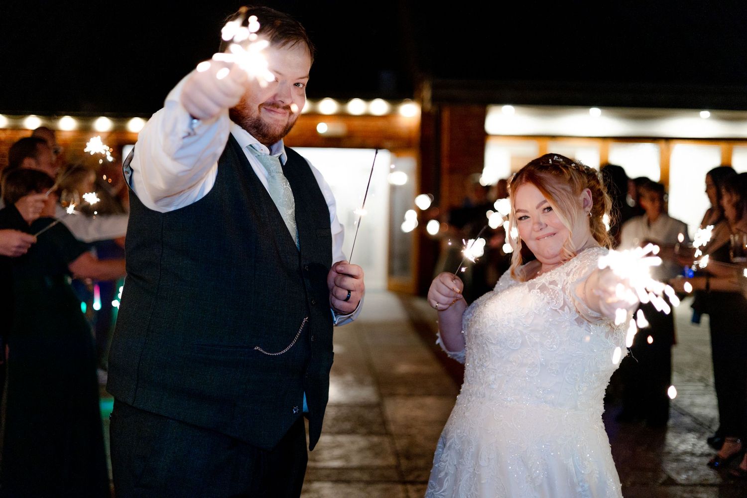 Newlyweds celebrate with sparkler exit during nighttime wedding festivities.