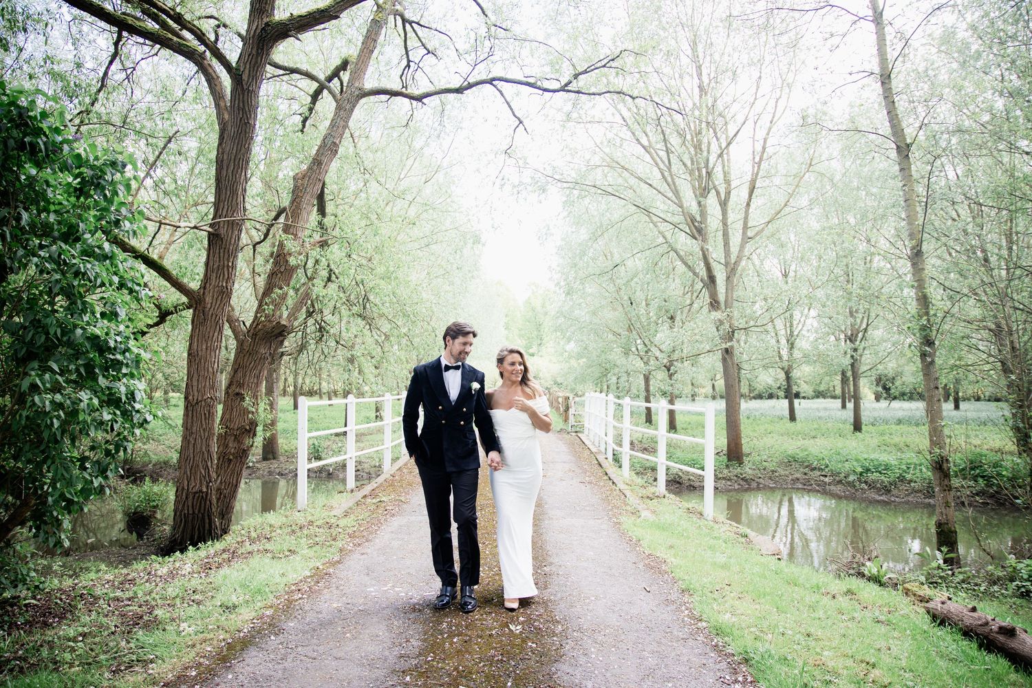 Scenic wedding portraits along a country path with white fencing and spring foliage.