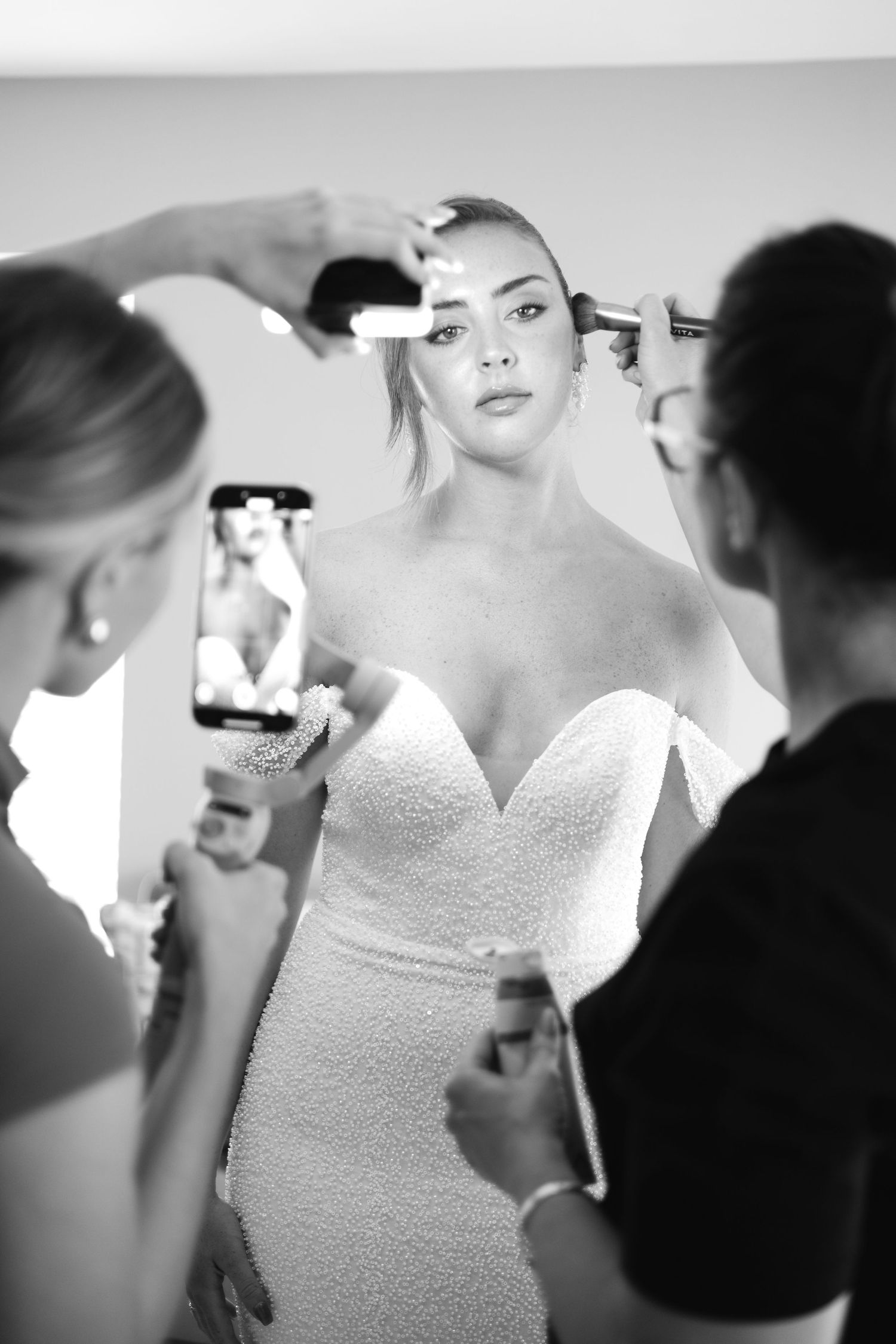 Behind the scenes of bridal makeup preparation in black and white.