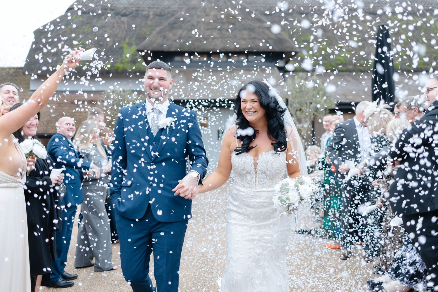 Wedding celebration with confetti being thrown in the air against a blue sky background.