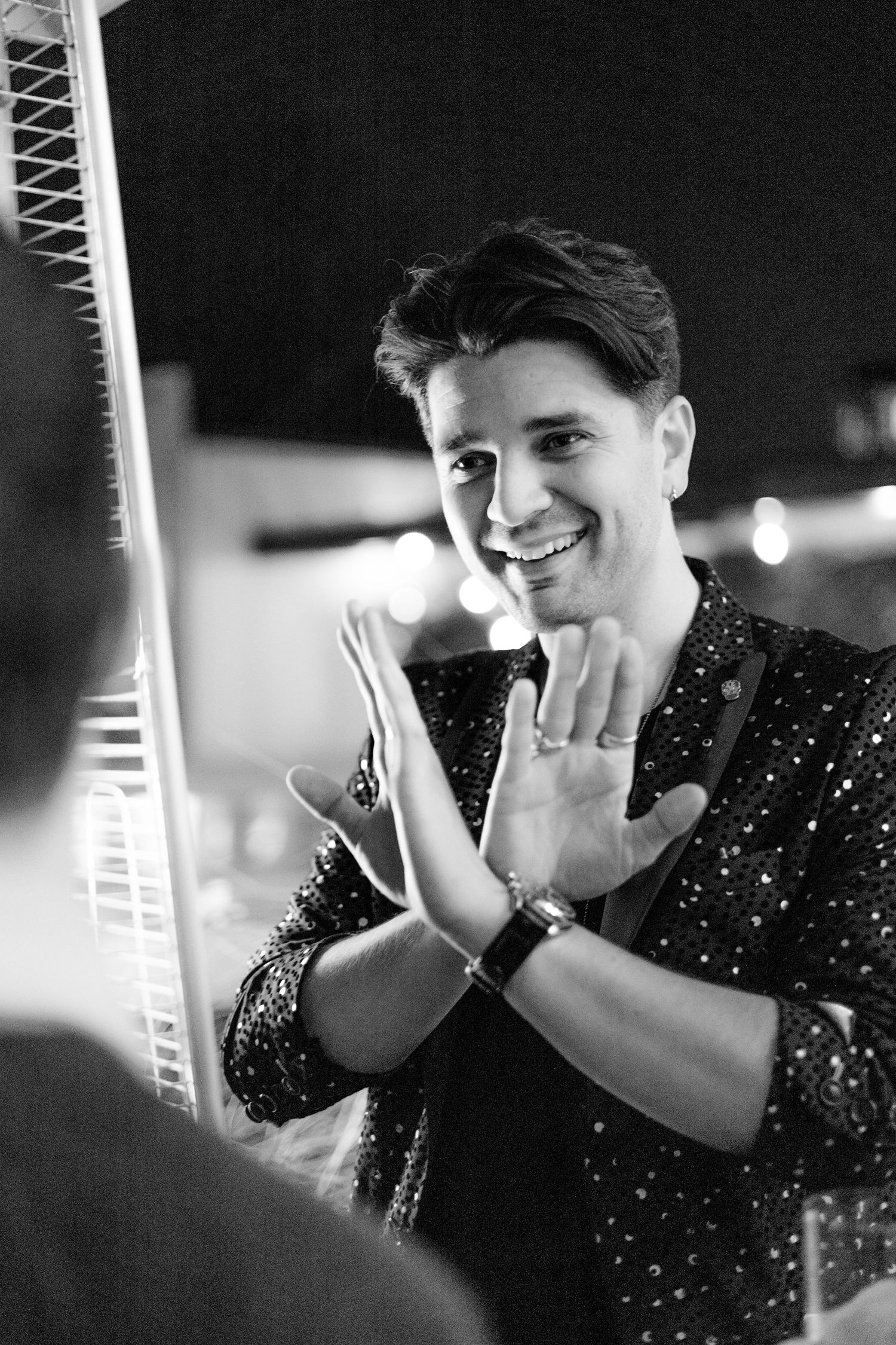 Black and white photo of someone making expressive hand gestures while smiling.