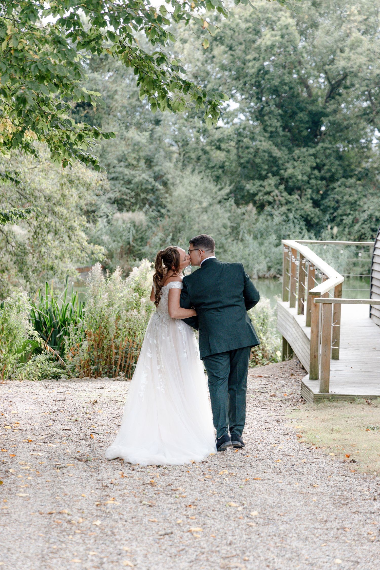 A couple walks along a garden pathway surrounded by lush greenery.