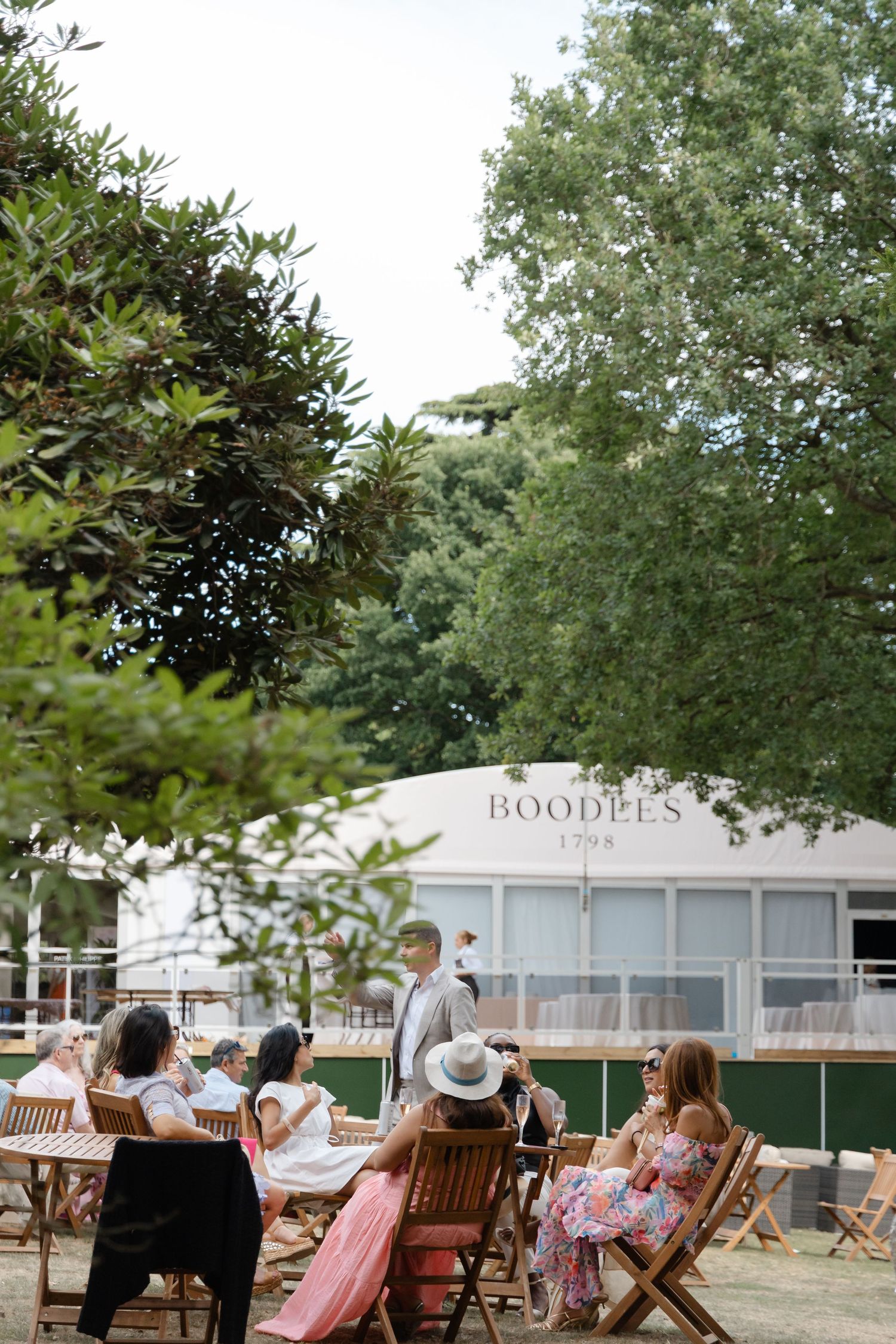 Guests relaxing in wooden deck chairs at an outdoor summer event venue.