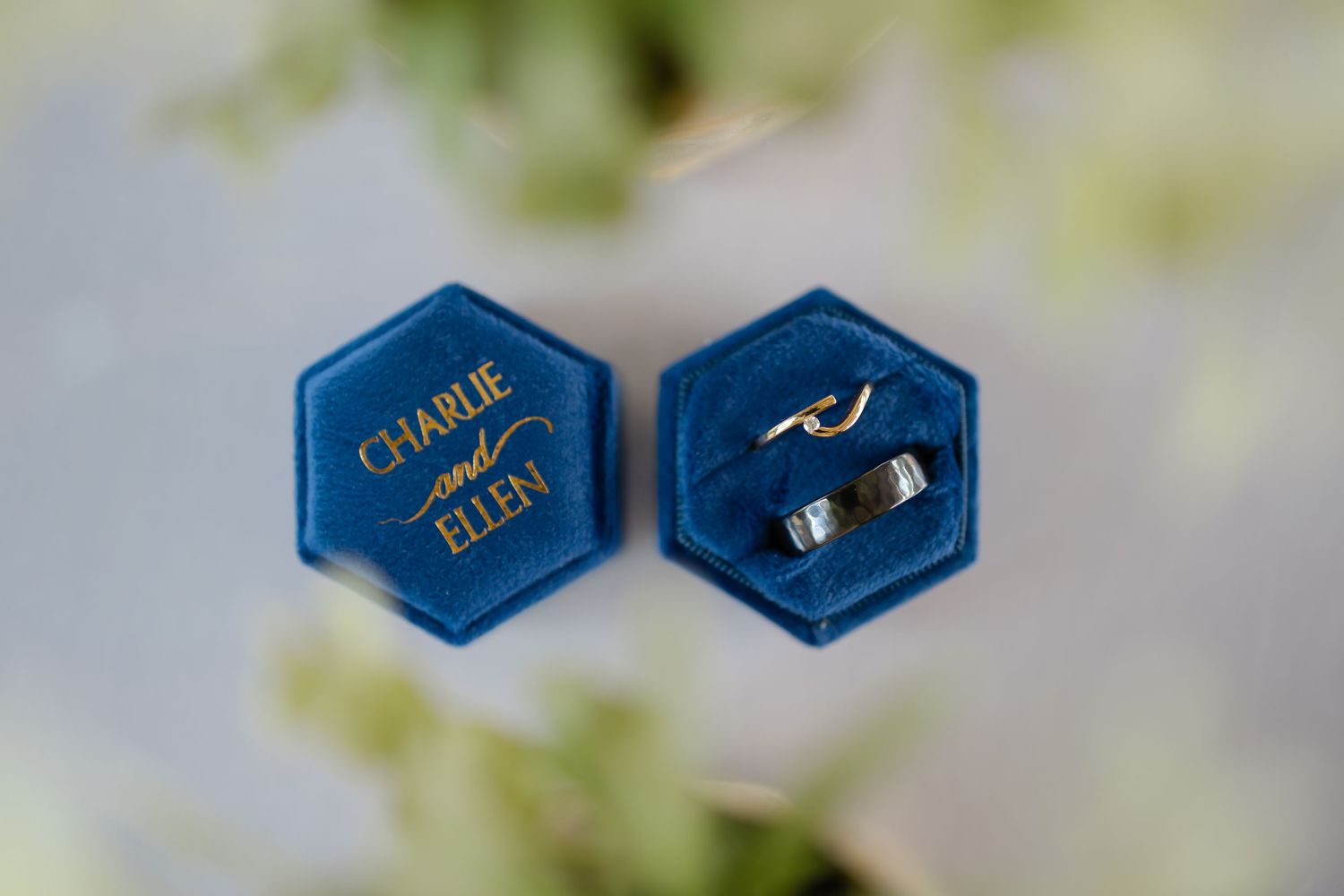 Close-up of elegant blue hexagonal wedding ring boxes with gold lettering.