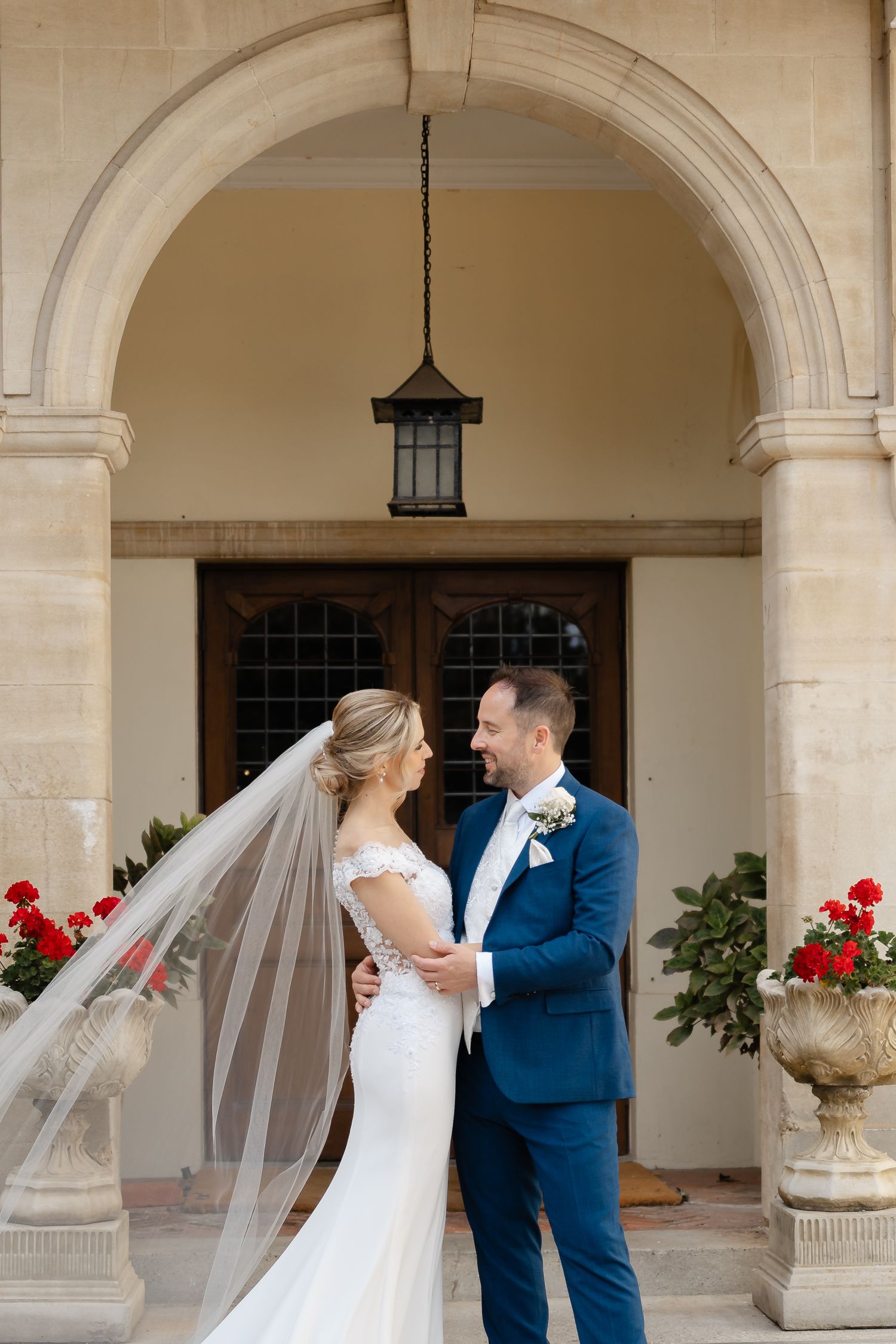 Elegant wedding portraits under stone archways with red floral accents.