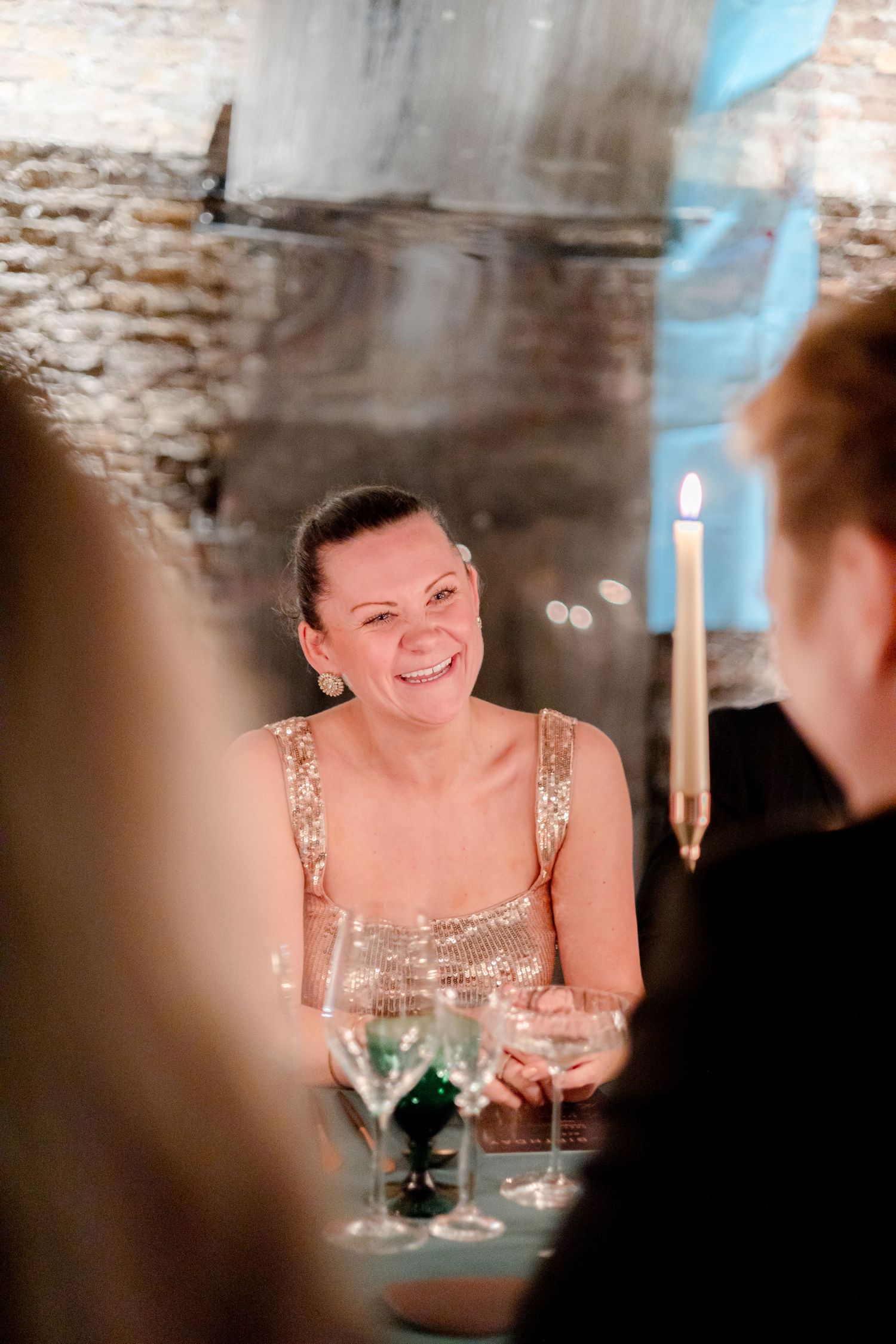 Guests enjoying a candlelit dinner at a rustic brick-walled venue.