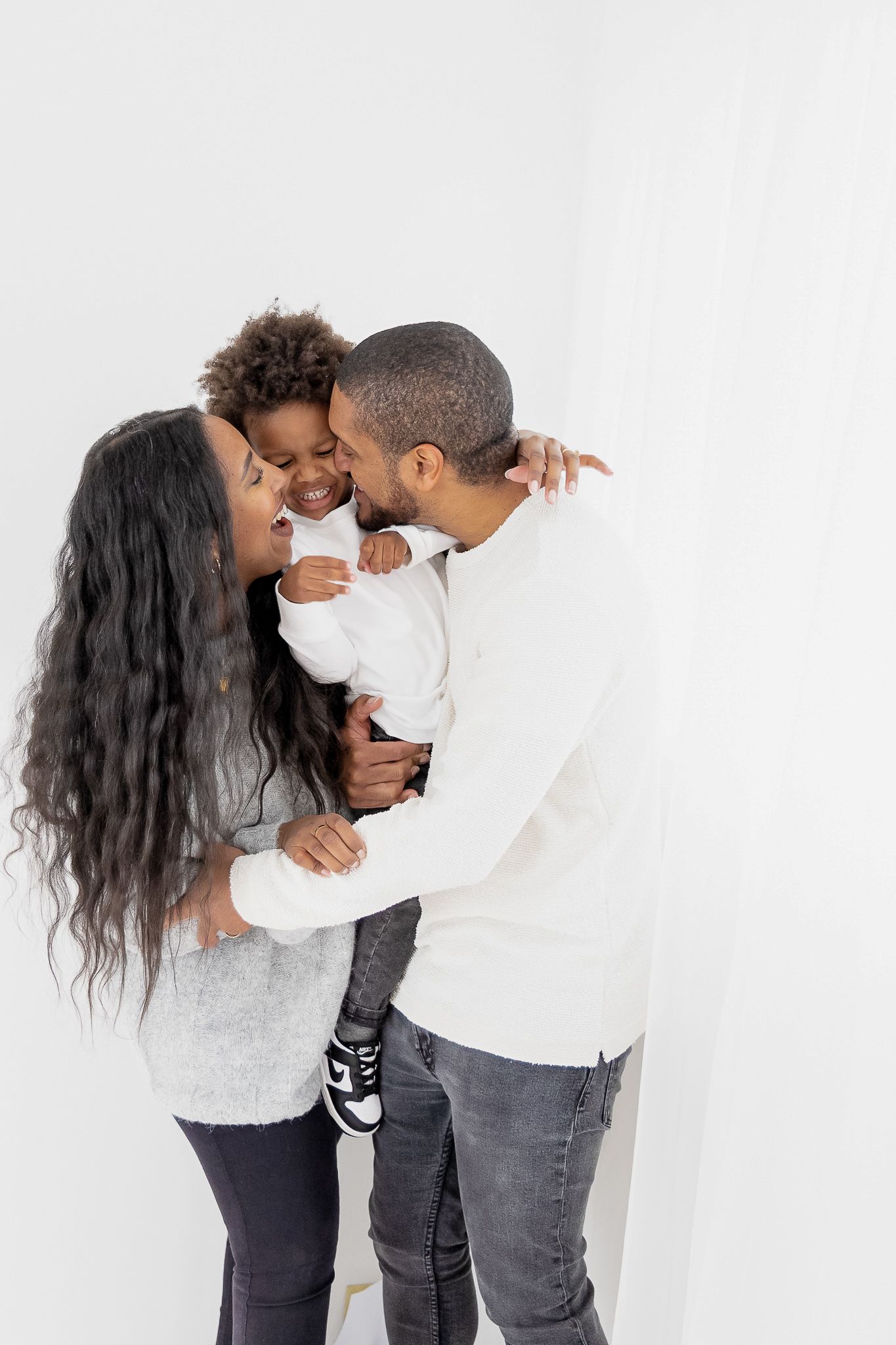 A family shares an intimate moment of joy and laughter against a white background.