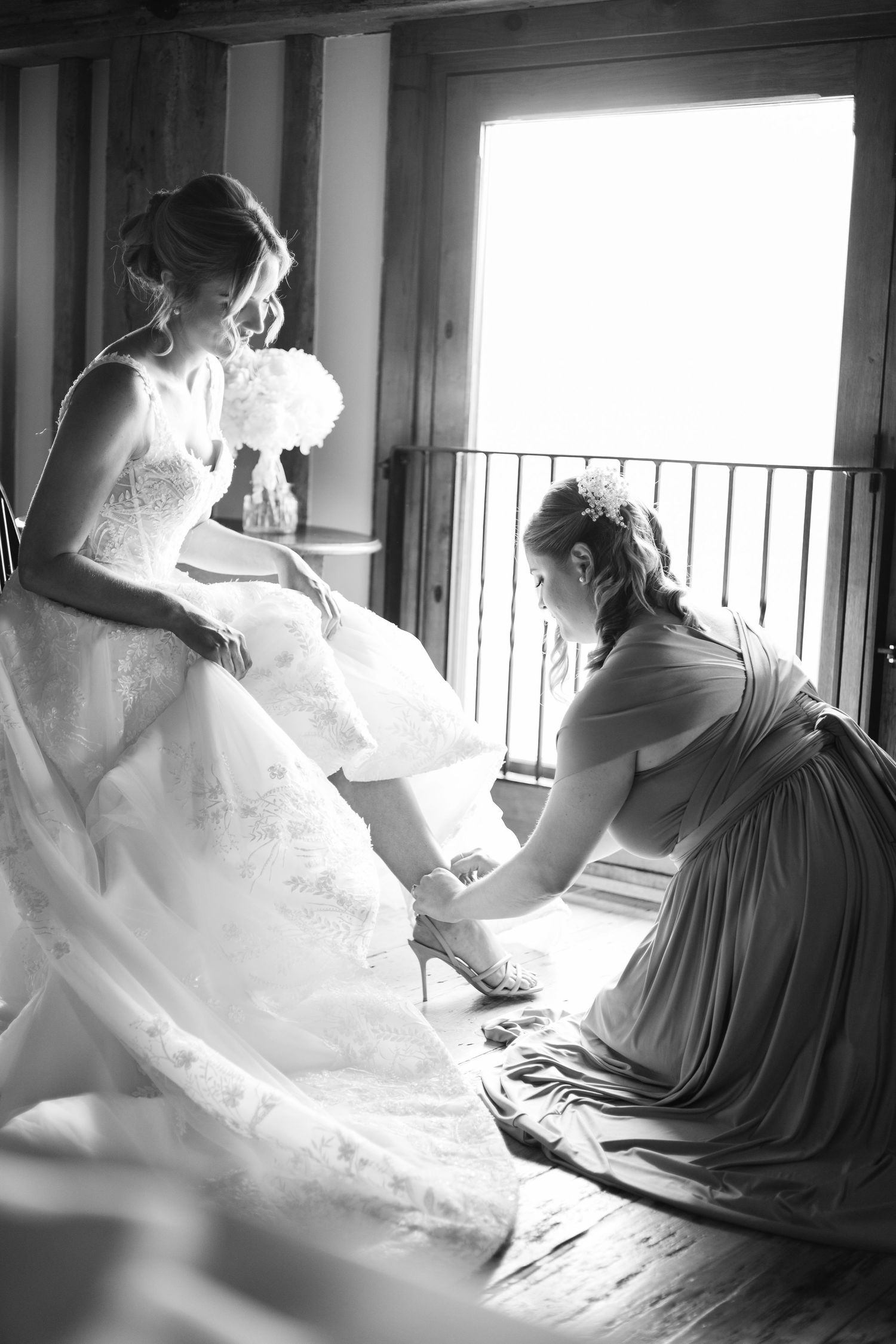 Artistic black and white photos of wedding dress preparation with dramatic window lighting.