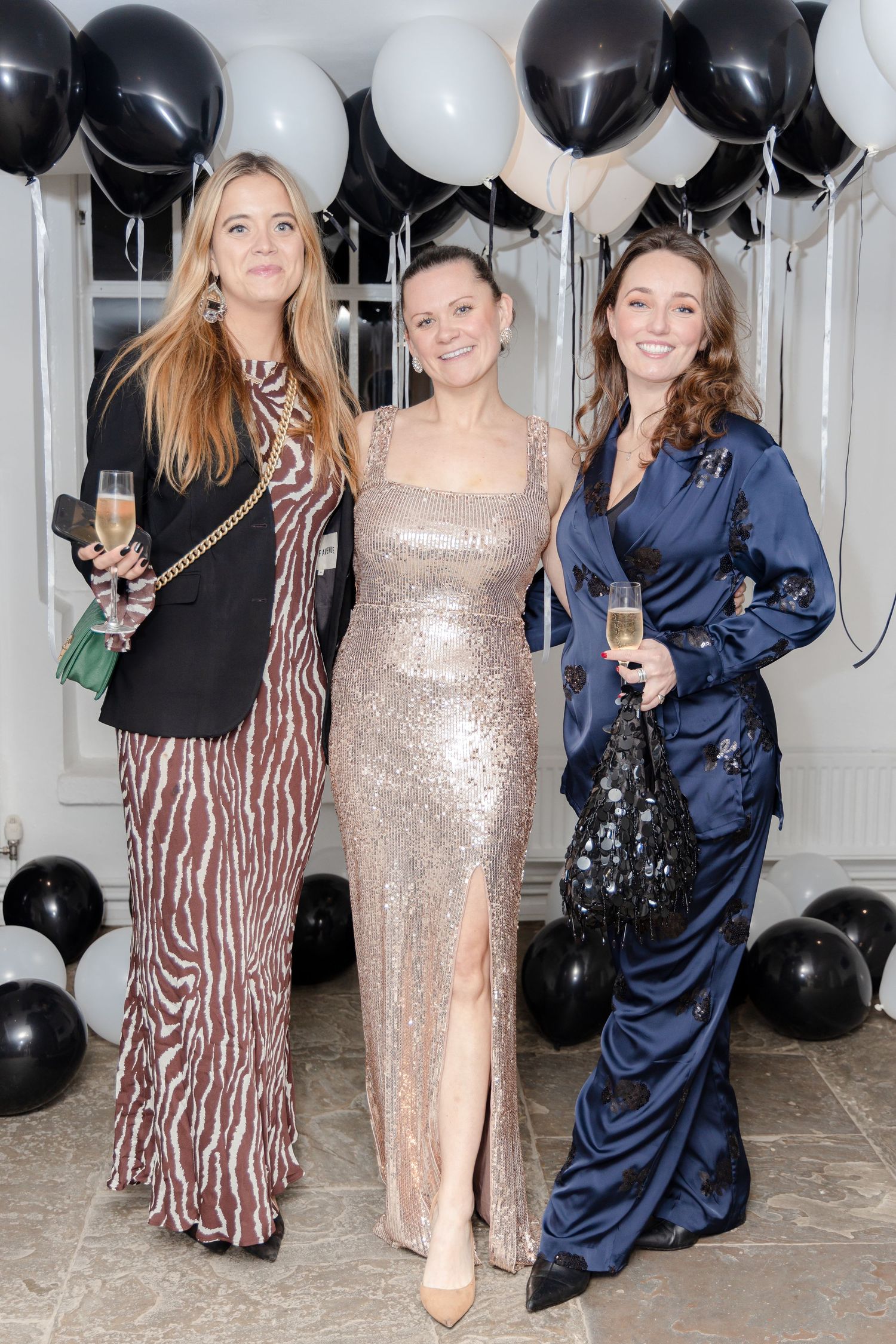 Group photo with black and white balloons and guests in sparkly formal attire.