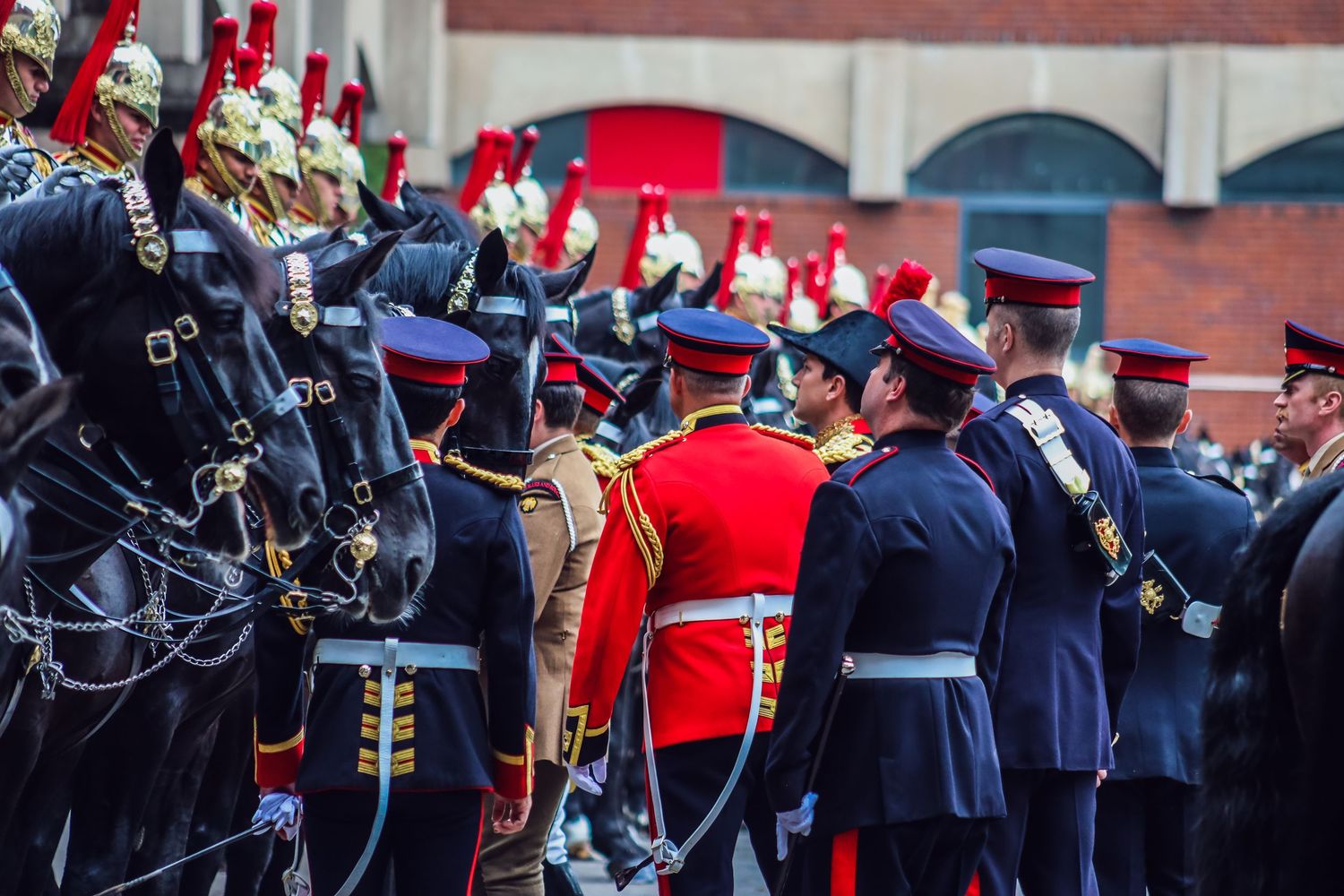 Military parade featuring uniformed guards marching in formation with red and gold ceremonial dress.